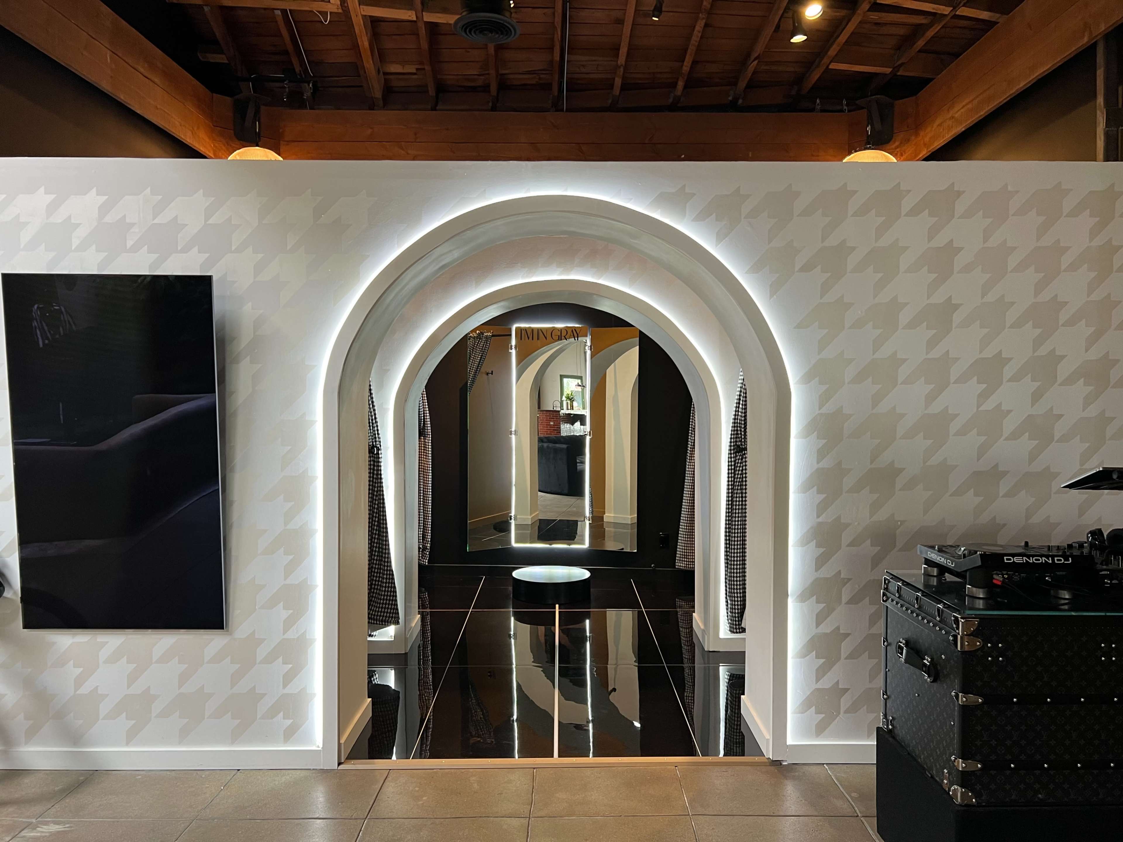 The image shows a modern interior featuring a series of arched openings leading to a reflective space, with textured walls and a sleek black floor.