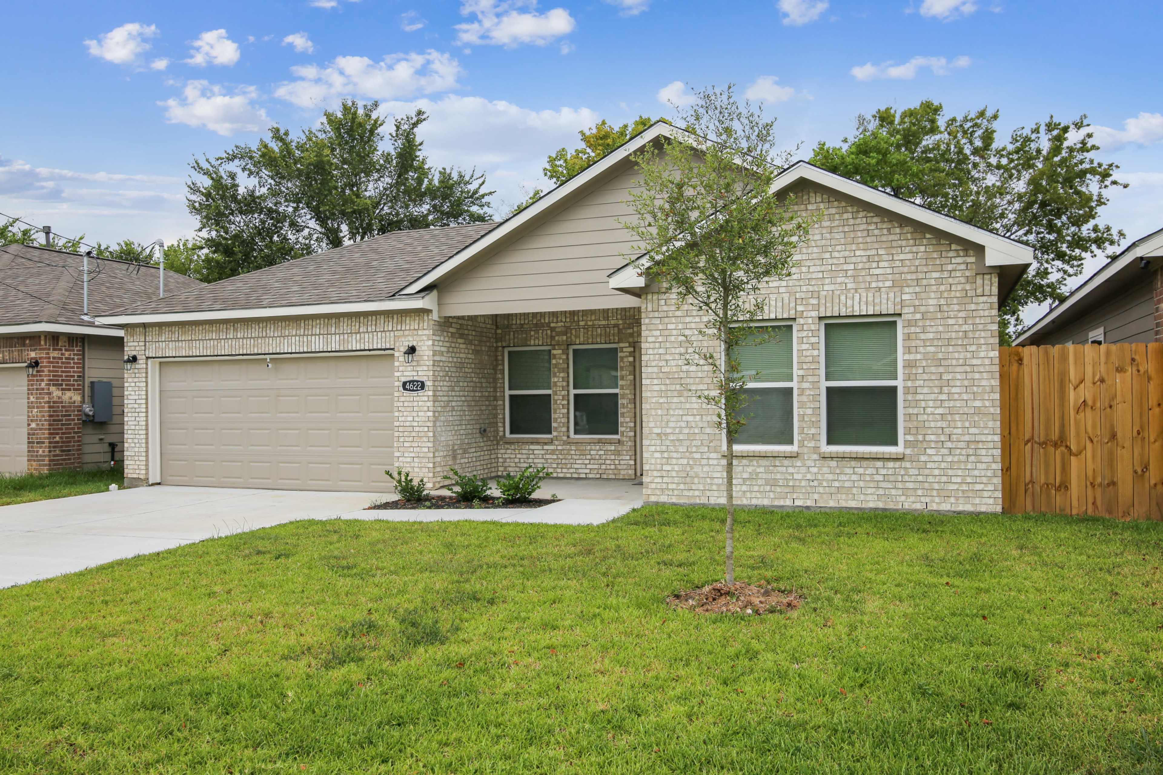 A single-story brick house with a two-car garage and a well-manicured lawn.