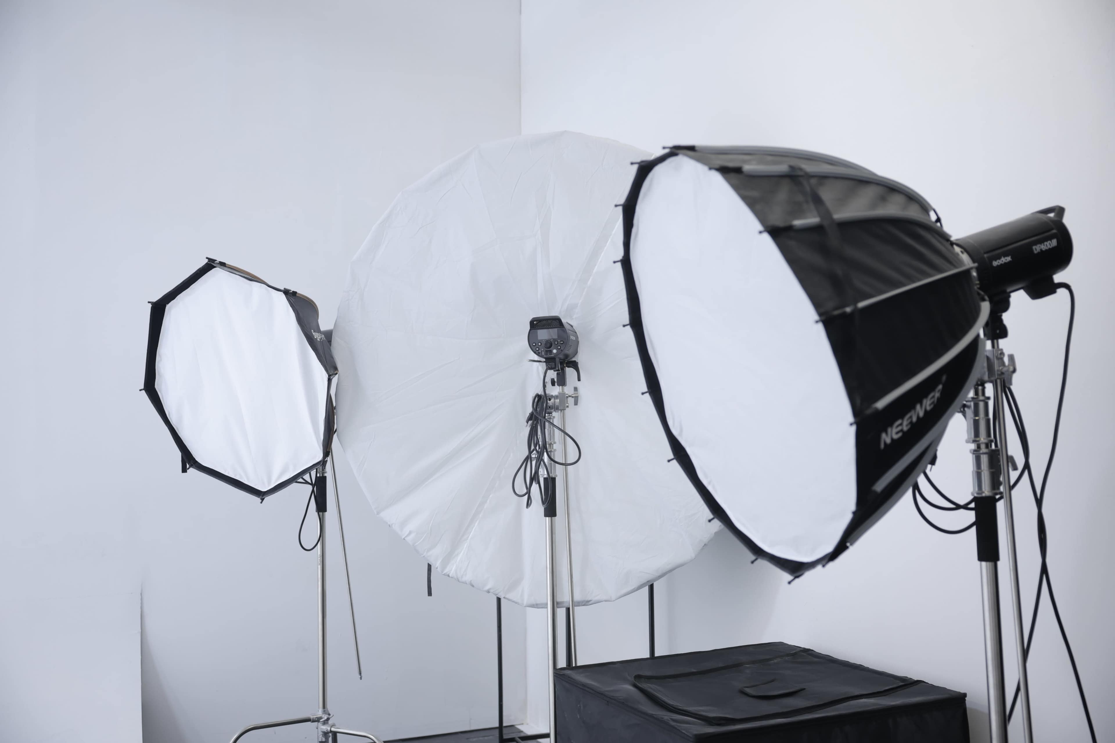 The image shows three photographic light softboxes arranged in a studio setting against a white backdrop.