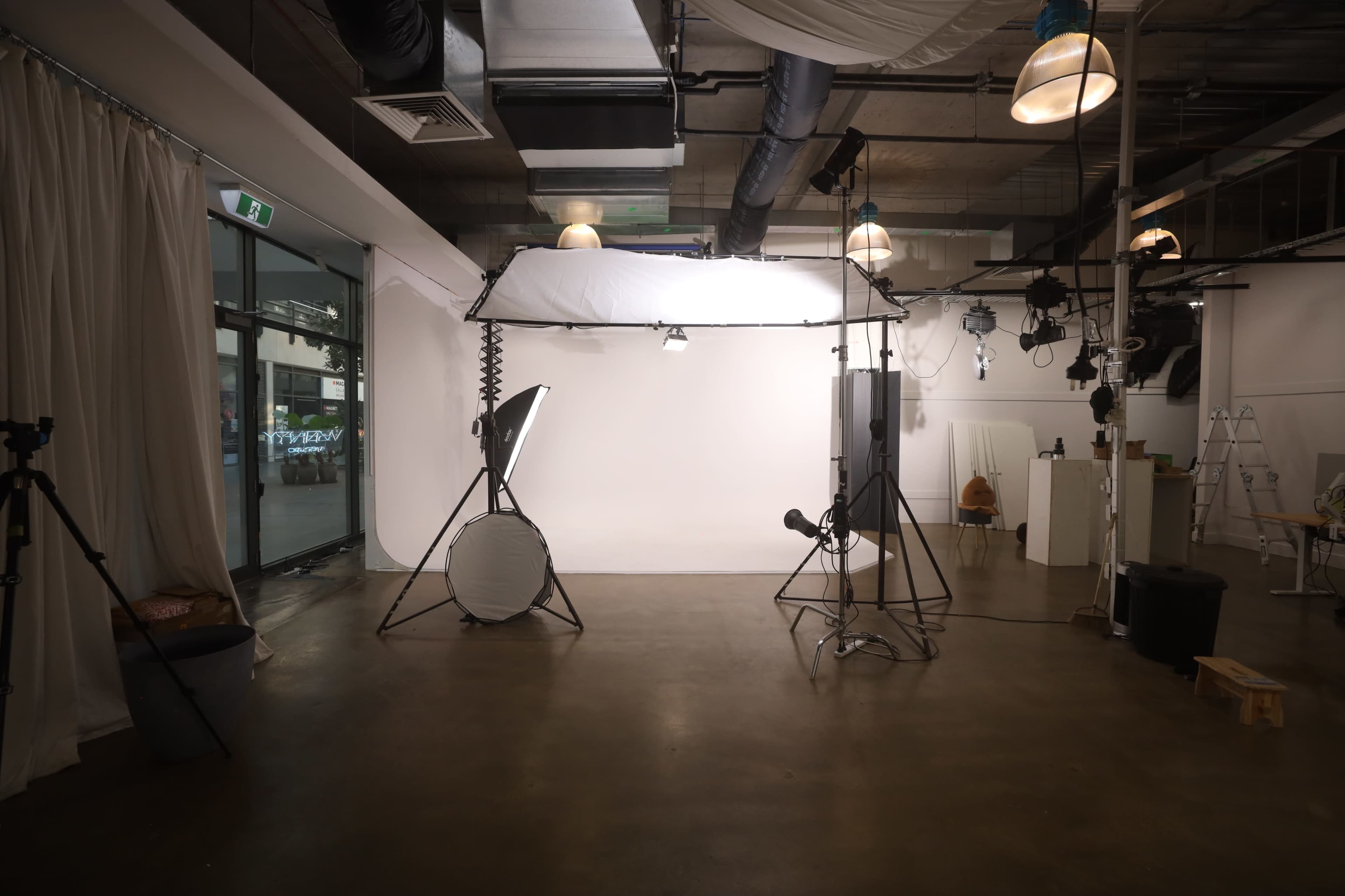 The image shows a photography studio featuring softbox lights, a backdrop, and various equipment arranged in a spacious, well-lit area.