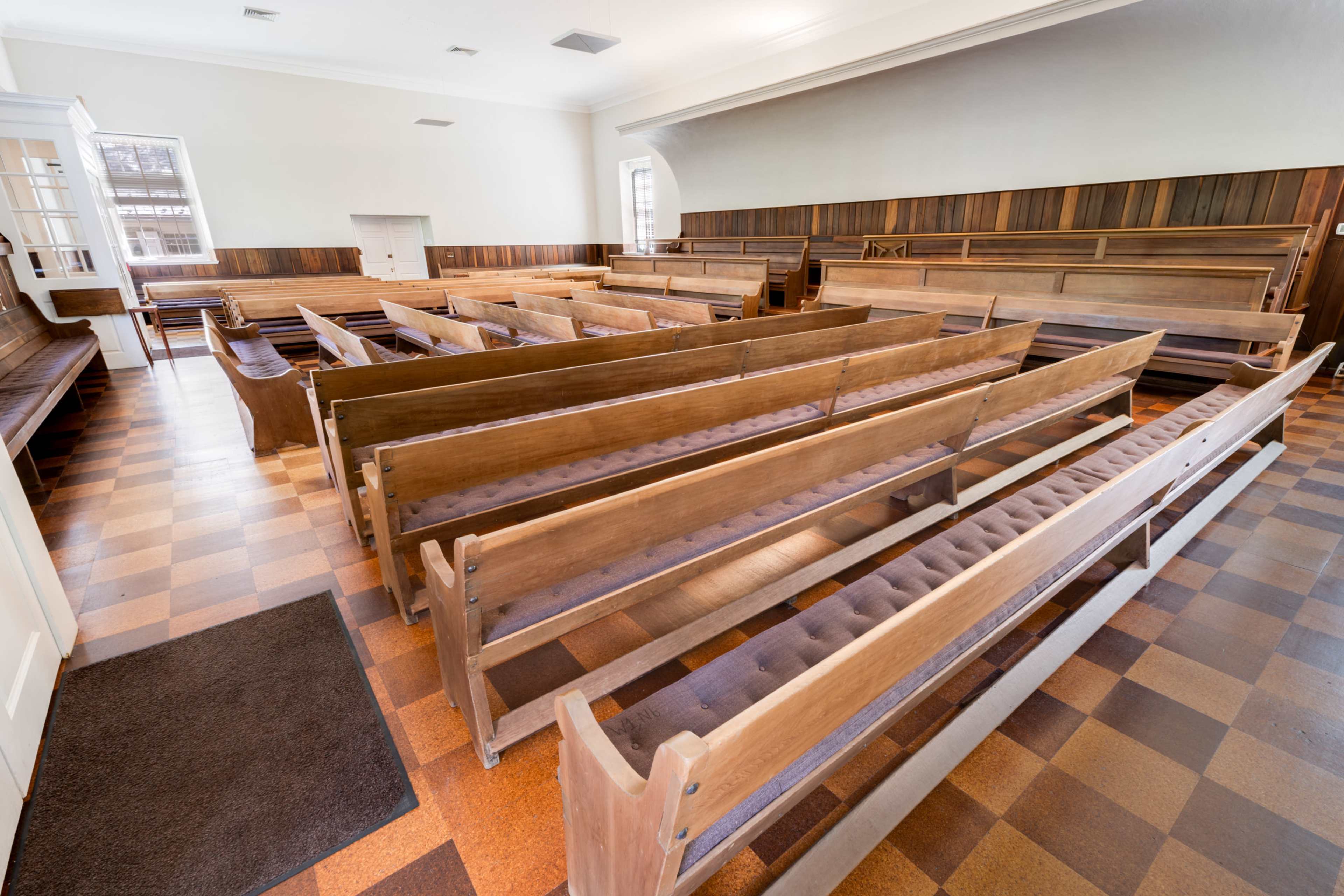 A spacious interior of a wooden chapel with several rows of wooden pews arranged neatly.