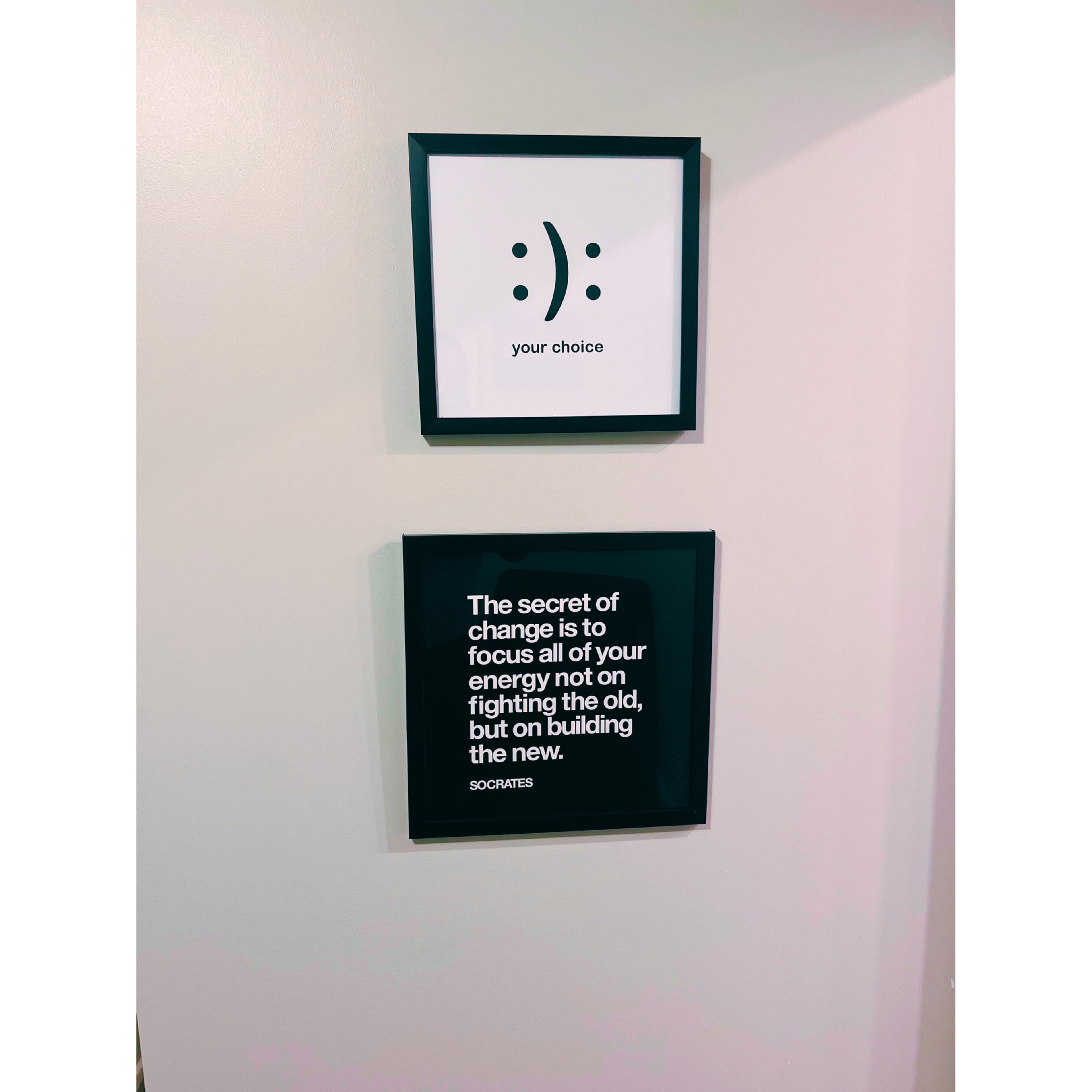 Two framed quotes on a wall; the top frame features a smiley face and the words "your choice," while the bottom frame contains a quote attributed to Socrates about change.