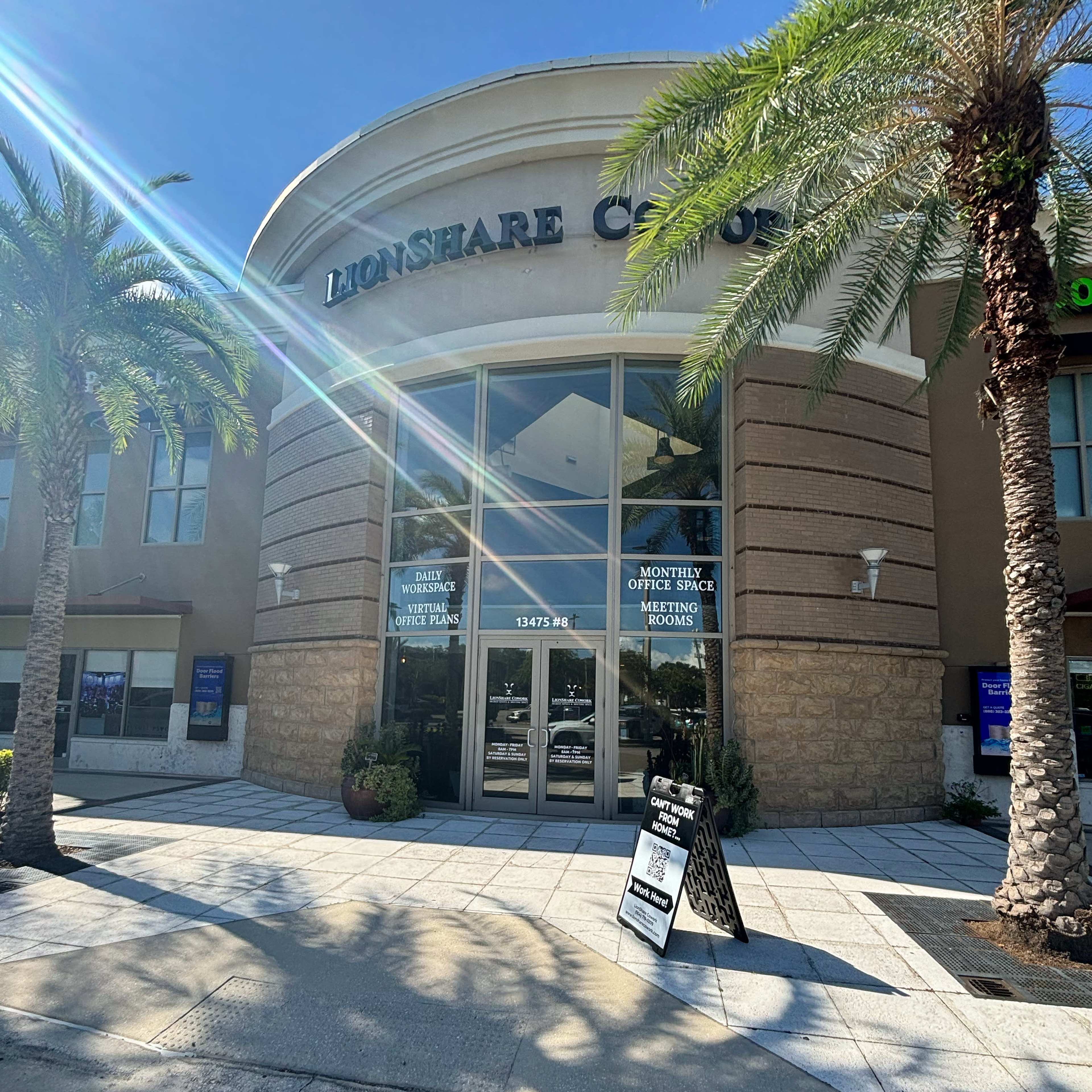 The image shows the entrance of the LionShare Casino, featuring large glass doors and palm trees lining the walkway.