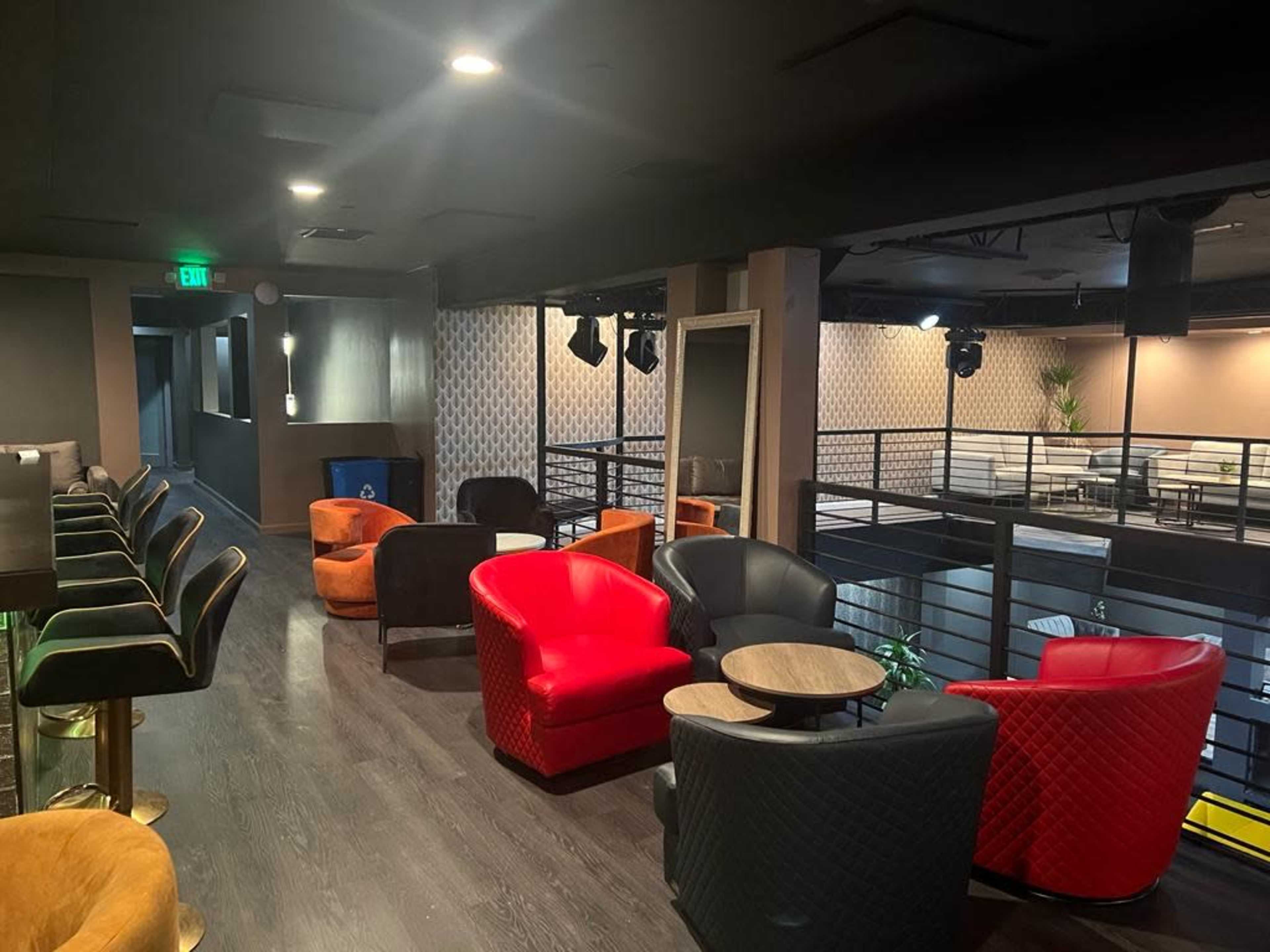 A modern lounge area with various seating options, including colorful chairs and small tables, under soft lighting.