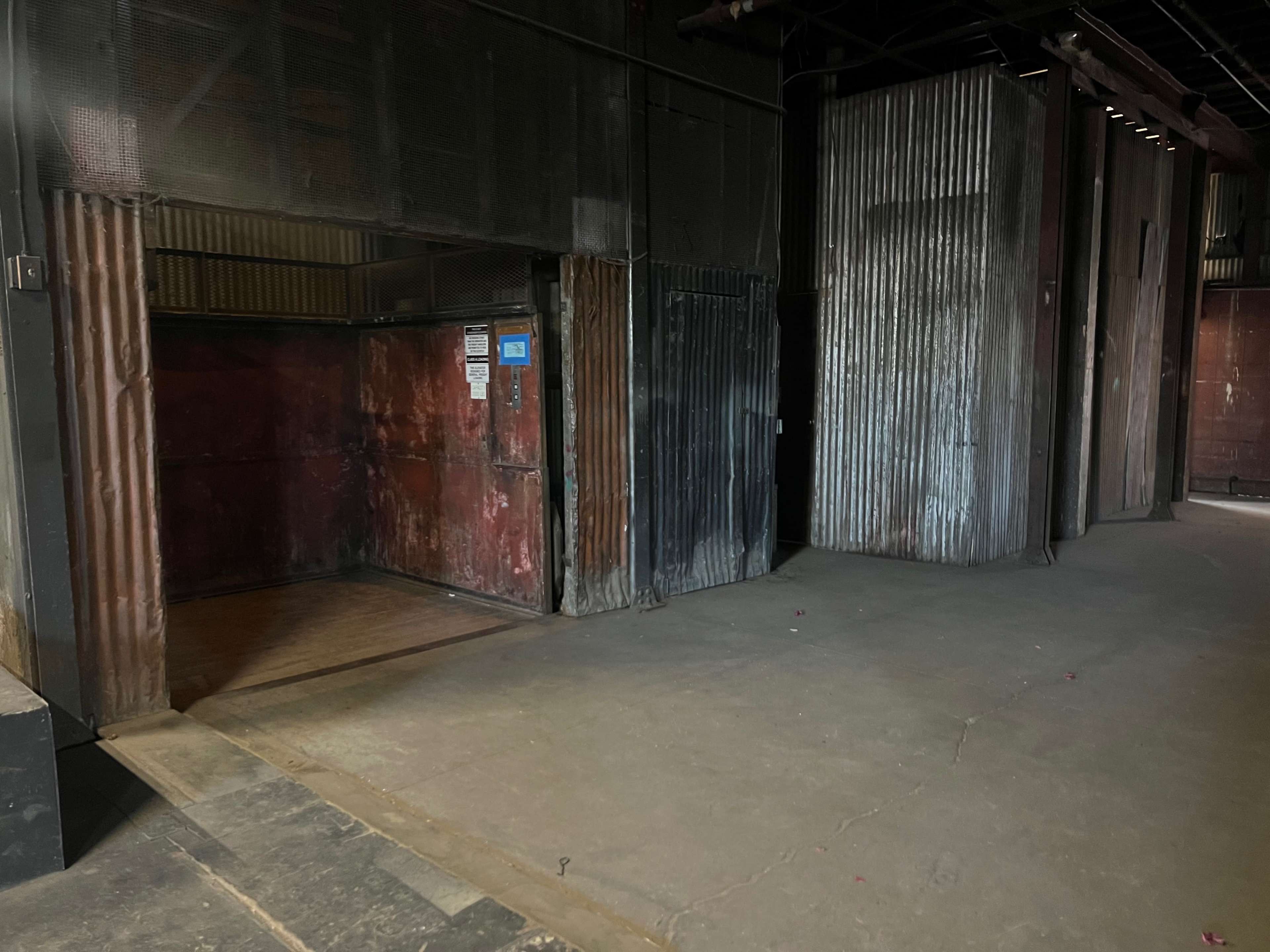 An industrial space with corrugated metal walls and an open doorway leading into a darker area.