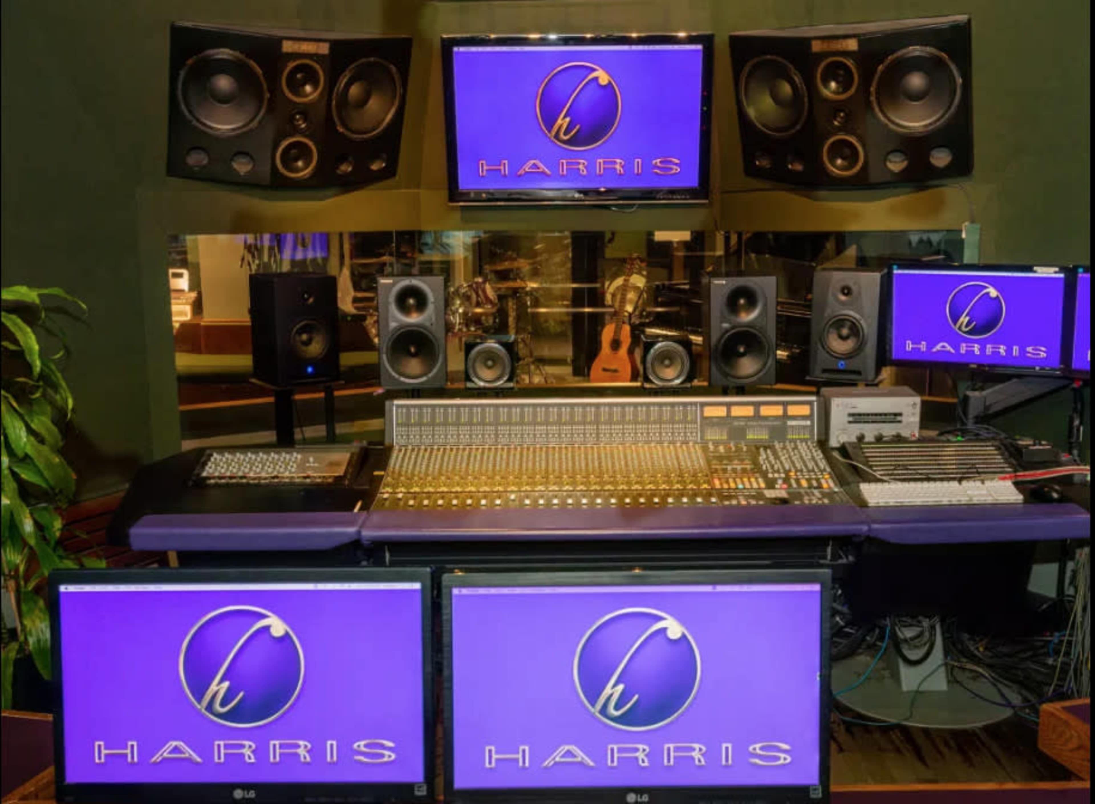 A sound studio setup featuring a mixing console, multiple monitors, and high-quality speakers arranged around a central workspace.