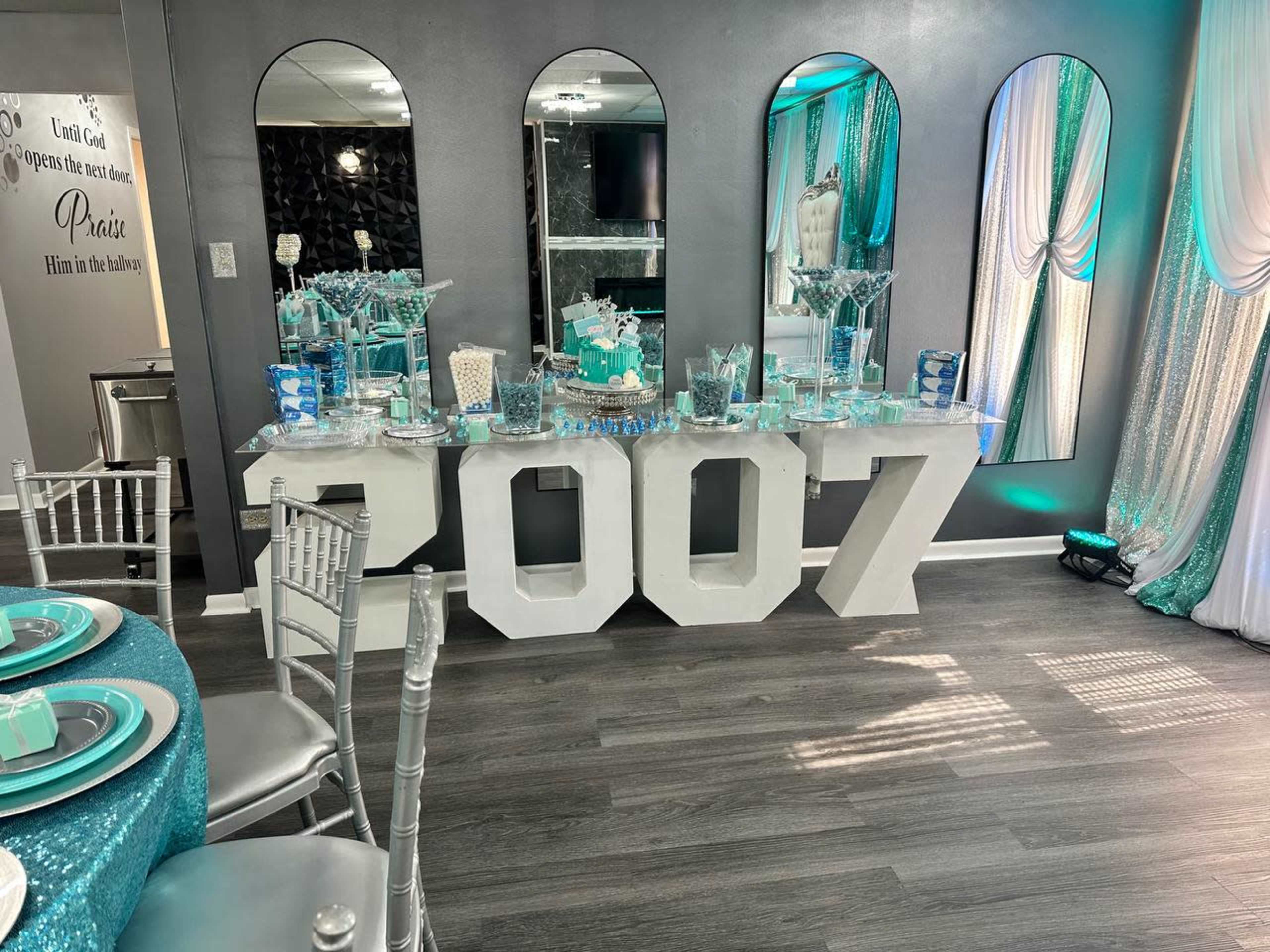 A banquet setup features a large table decorated with the number "2007," surrounded by chairs, elegant tableware, and draped fabrics in a themed color scheme.