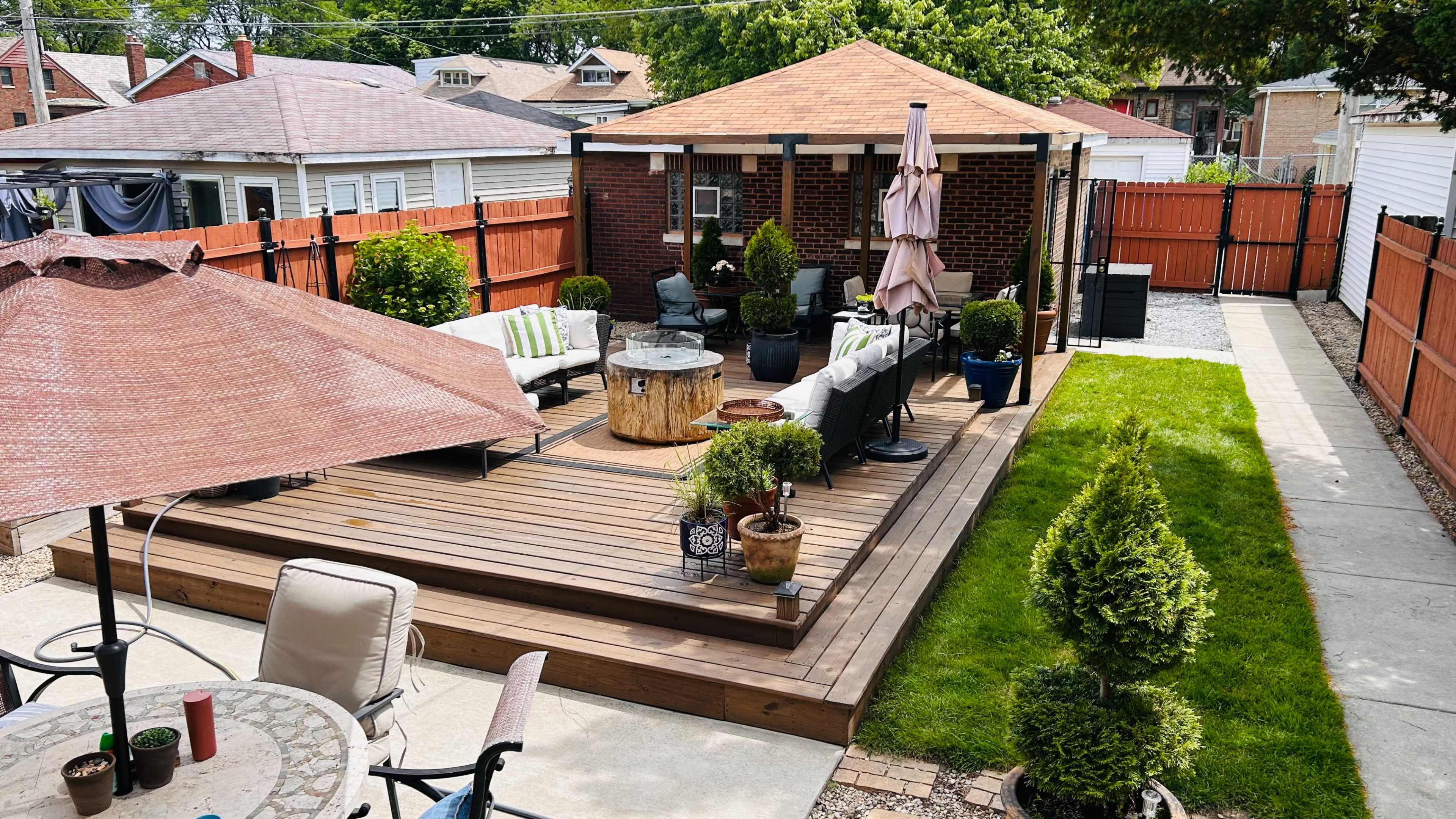 The image shows a backyard deck area with a gazebo, seating arrangements, and landscaped greenery.