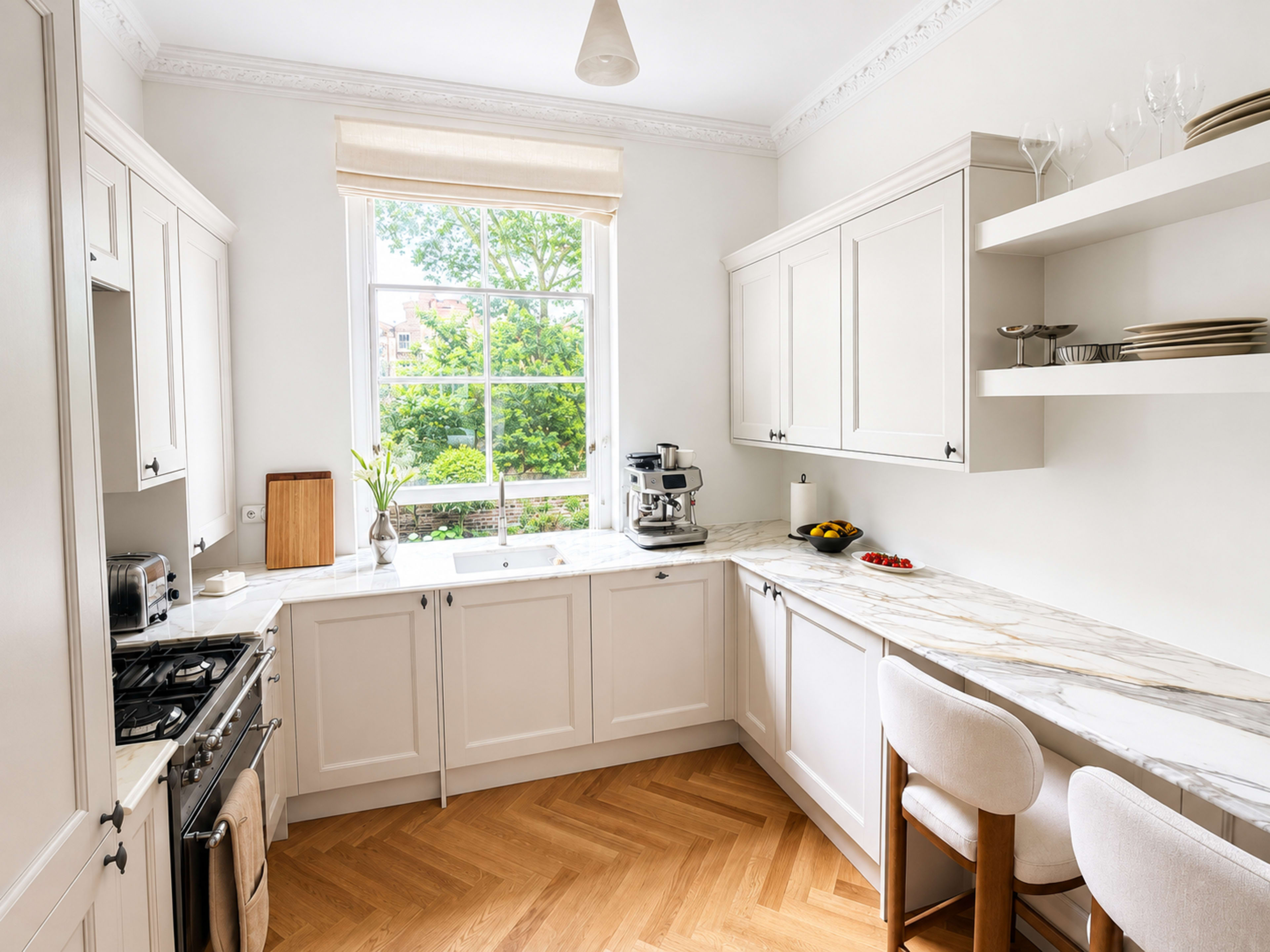The image shows a bright kitchen featuring white cabinetry, a marble countertop, and a large window with a view of greenery outside.