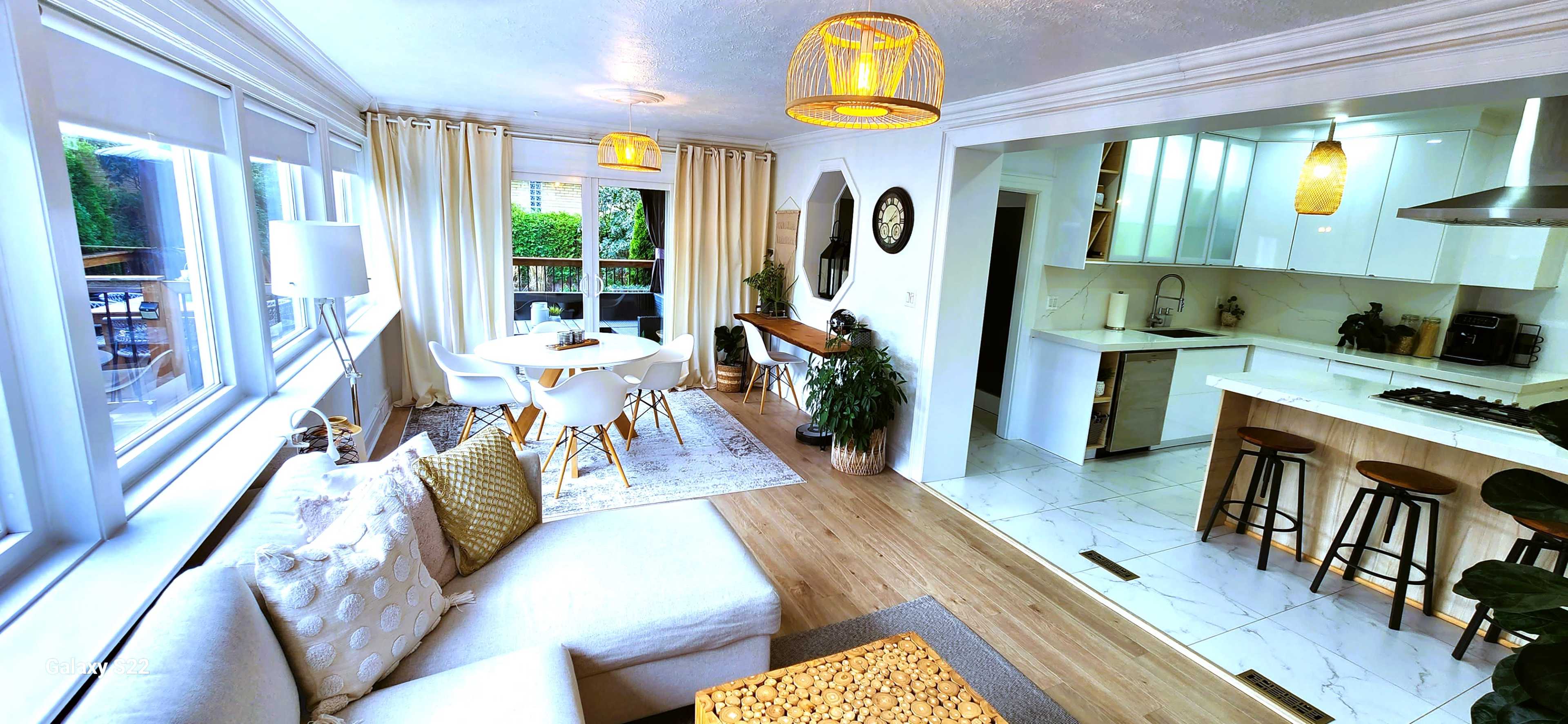 A bright, open-concept living and dining area featuring a modern kitchen, a cozy seating area, and a dining table surrounded by chairs.