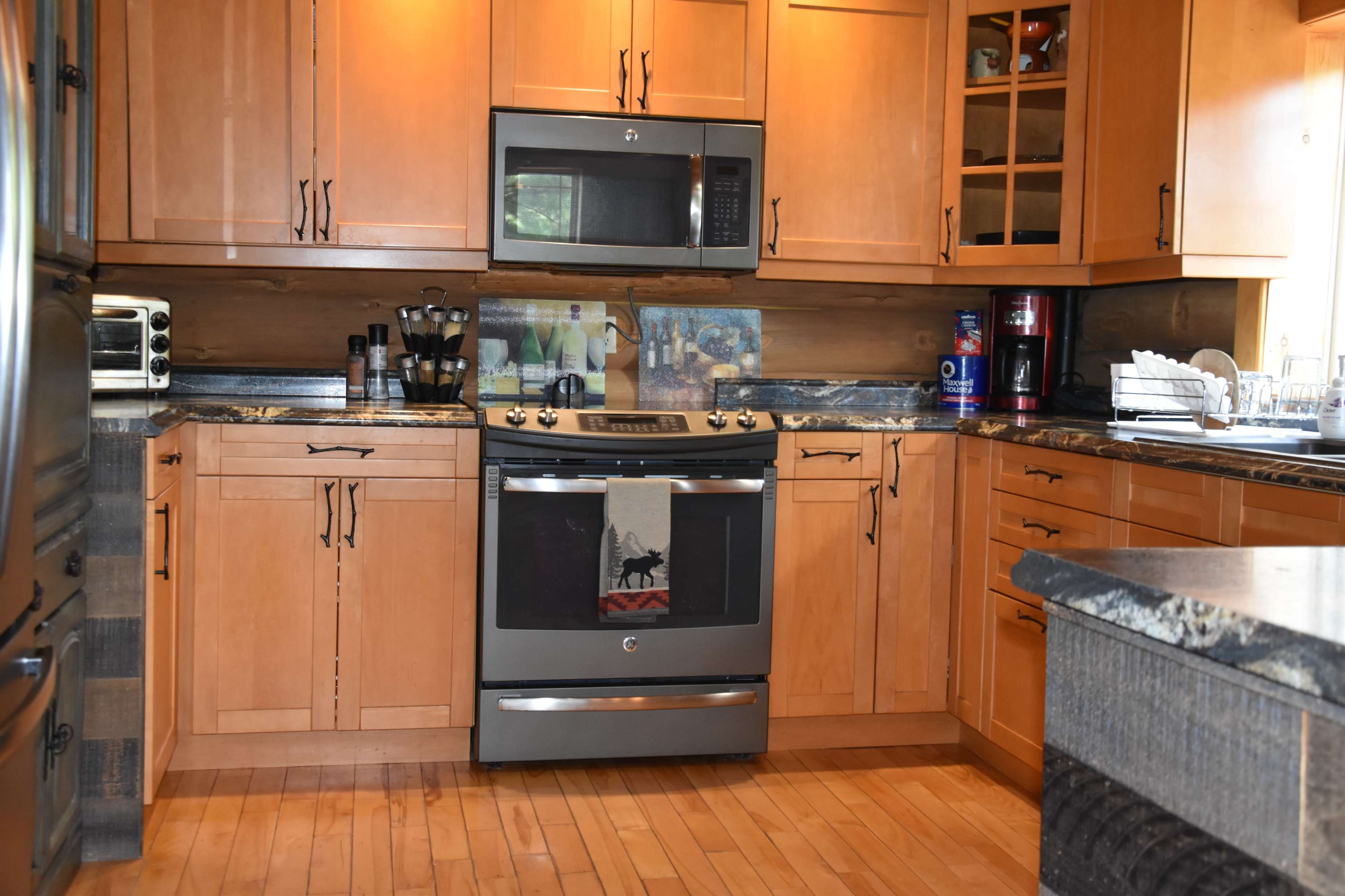A modern kitchen featuring wooden cabinets, a stainless steel stove, and various kitchen appliances arranged on the countertops.