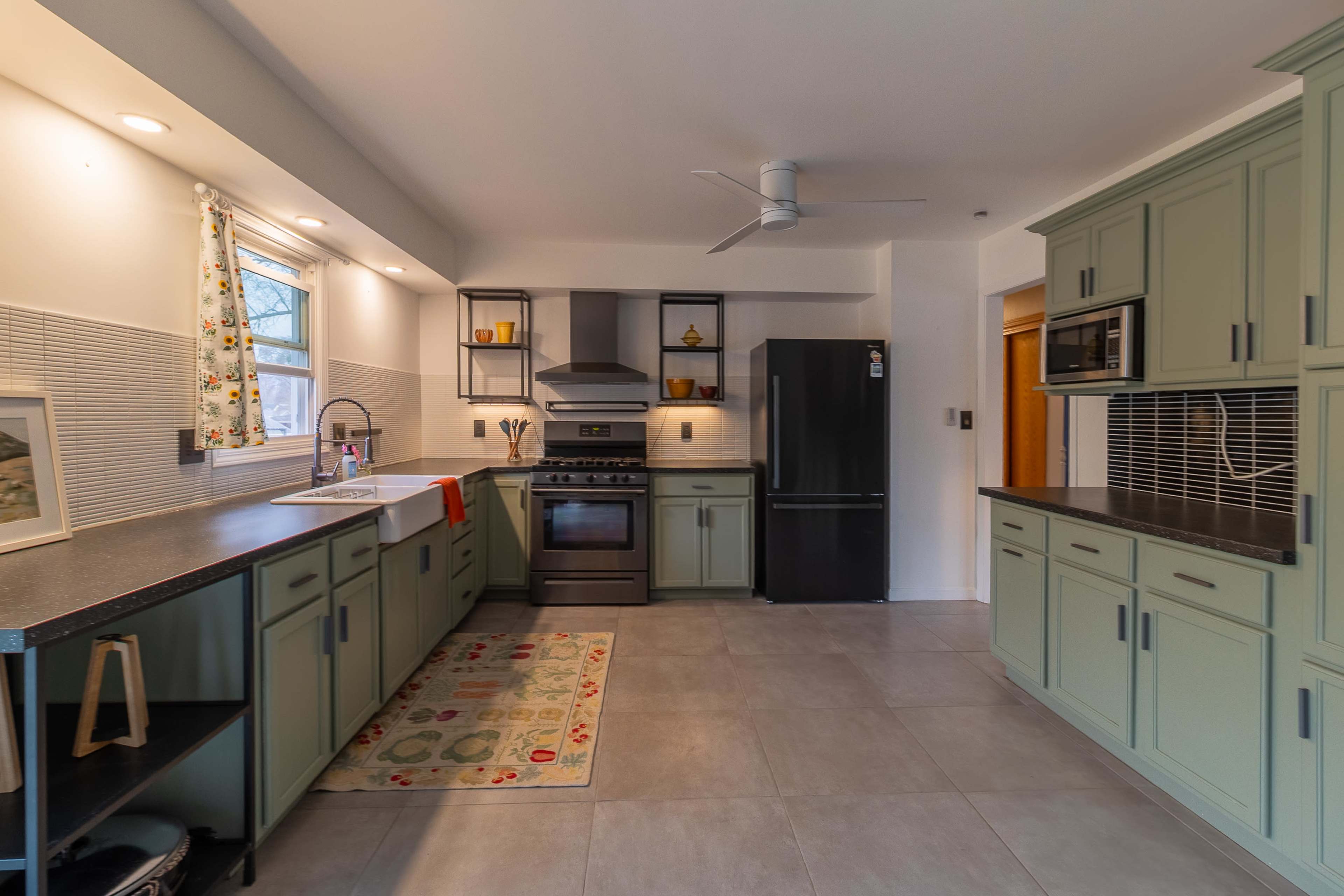 The kitchen features green cabinetry, stainless steel appliances, and a tile floor.
