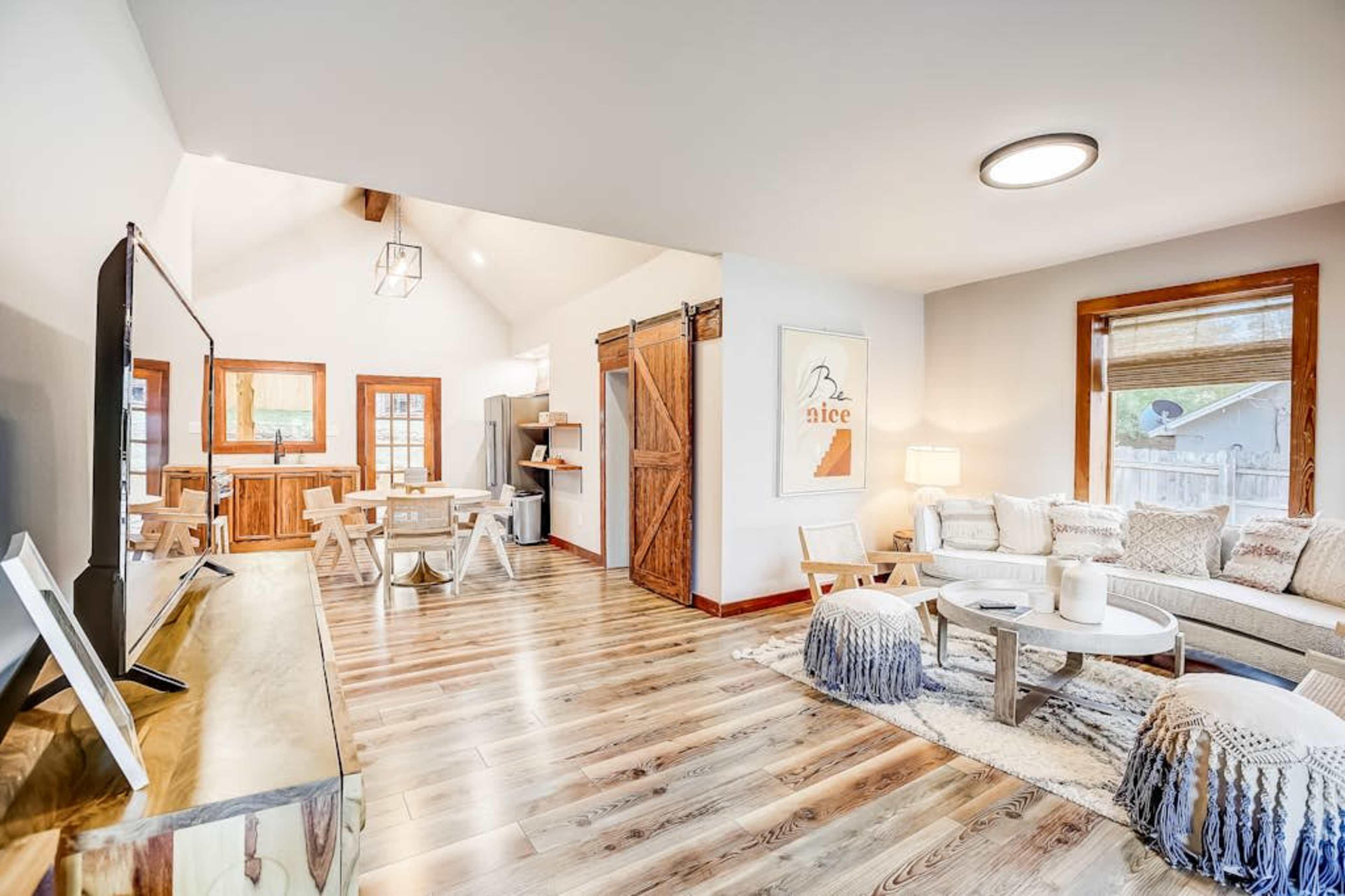 A well-furnished living room features a light-colored sofa, wooden accents, and large windows letting in natural light.