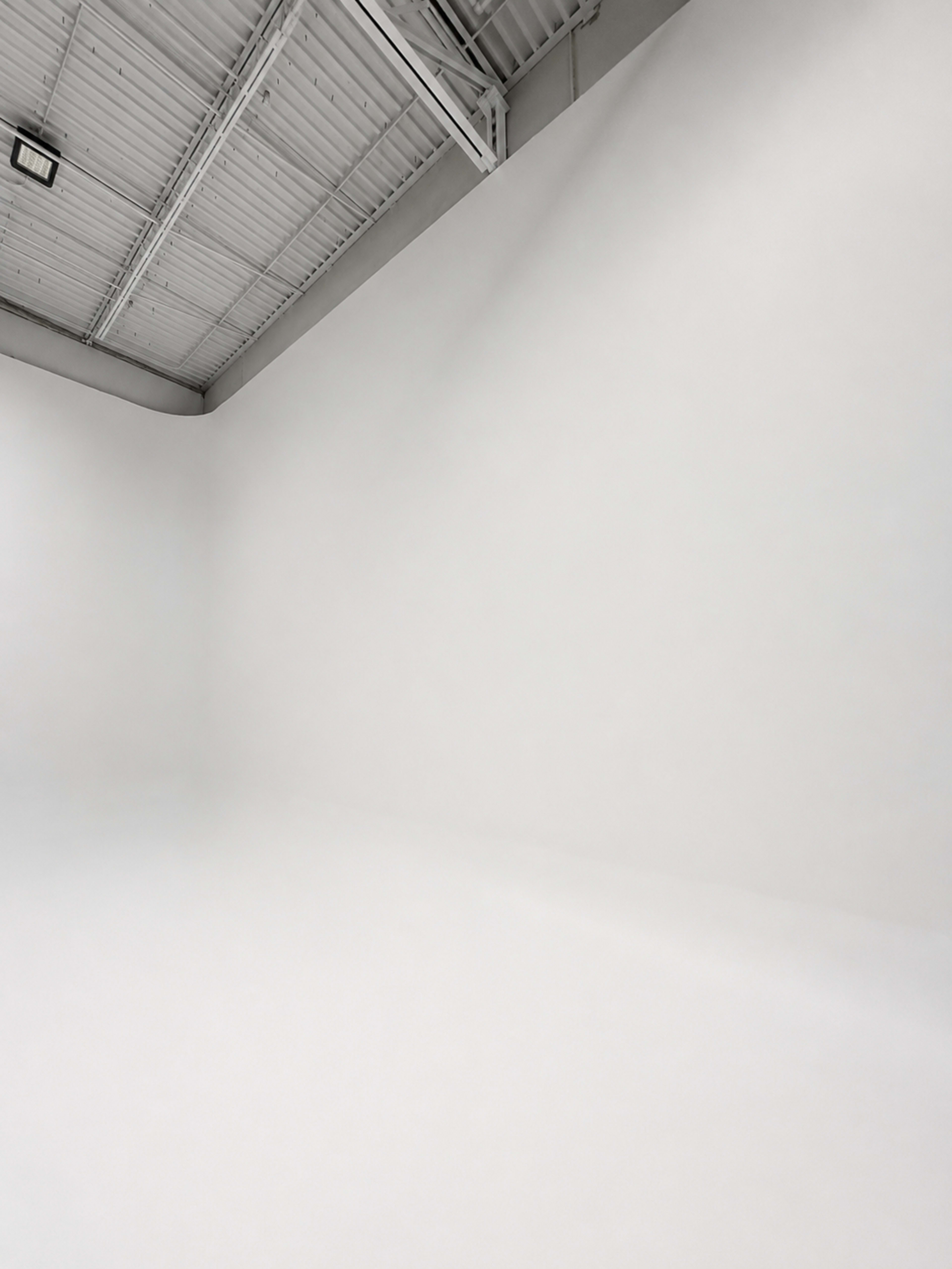 The image shows an empty room with white walls, a white floor, and a visible ceiling.