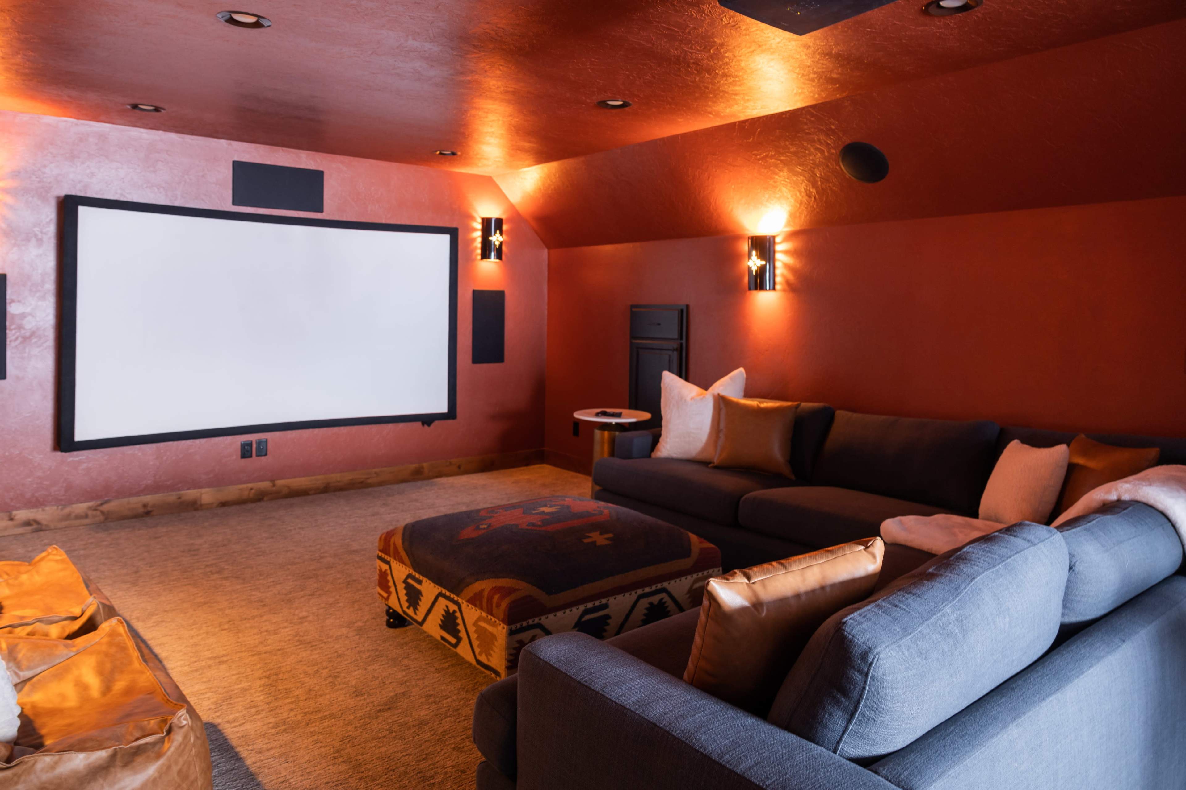 A cozy home theater room with a large projection screen, comfortable seating, and warm lighting.