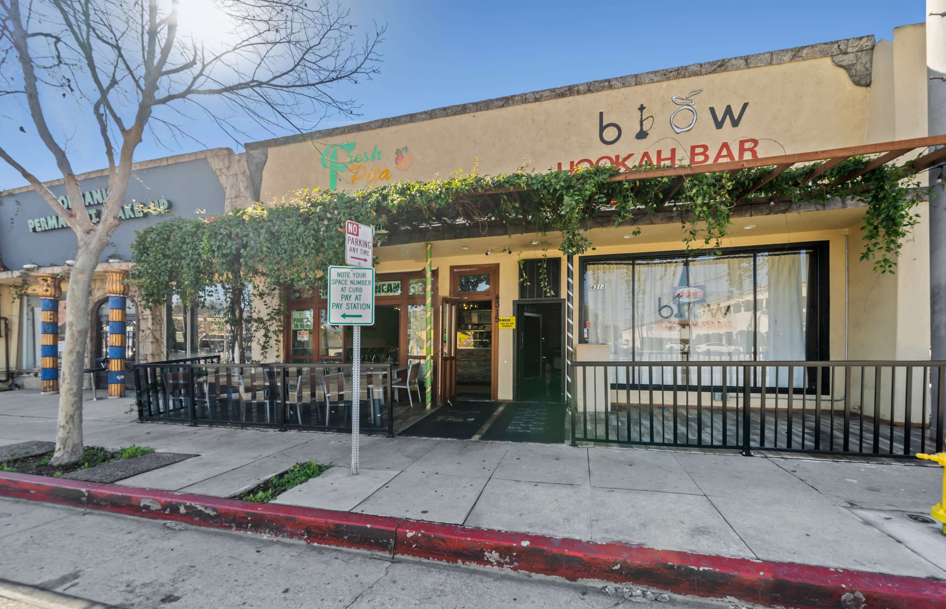 A hookah bar with outdoor seating, surrounded by shops on a city street.