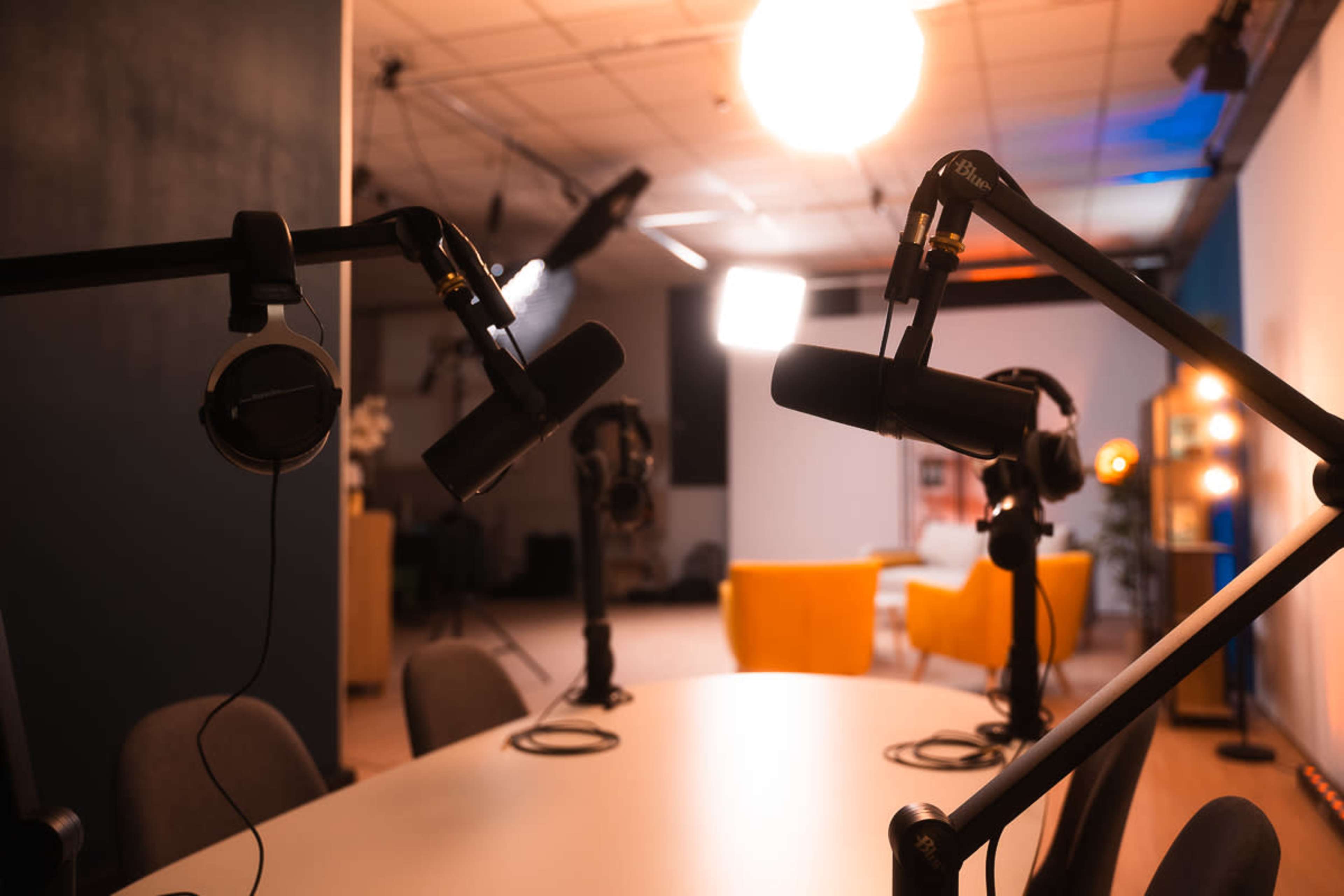 A microphone setup is positioned around a table in a brightly lit podcast recording studio.