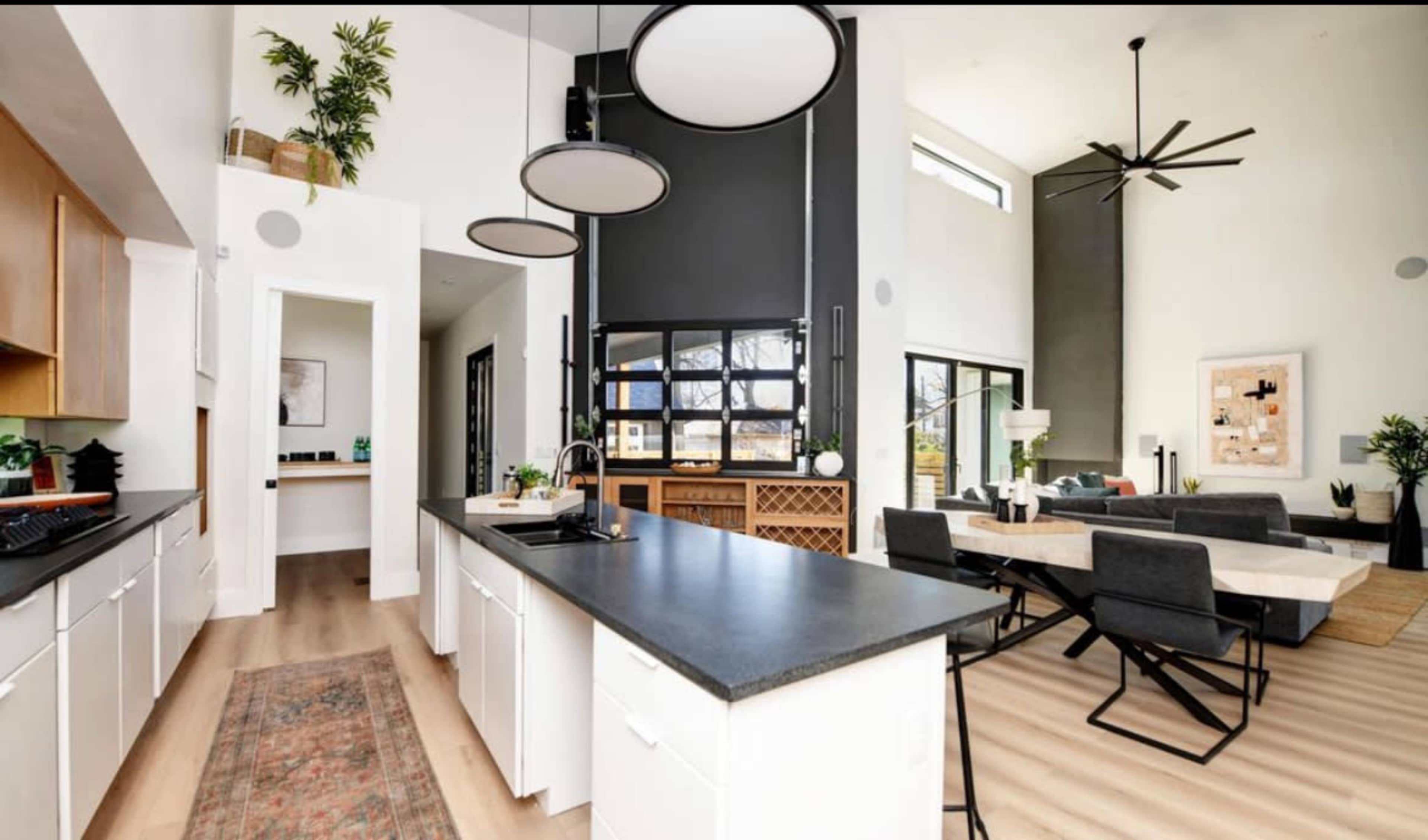 A modern open-concept kitchen and living area featuring a central island, sleek cabinetry, and a spacious dining table.