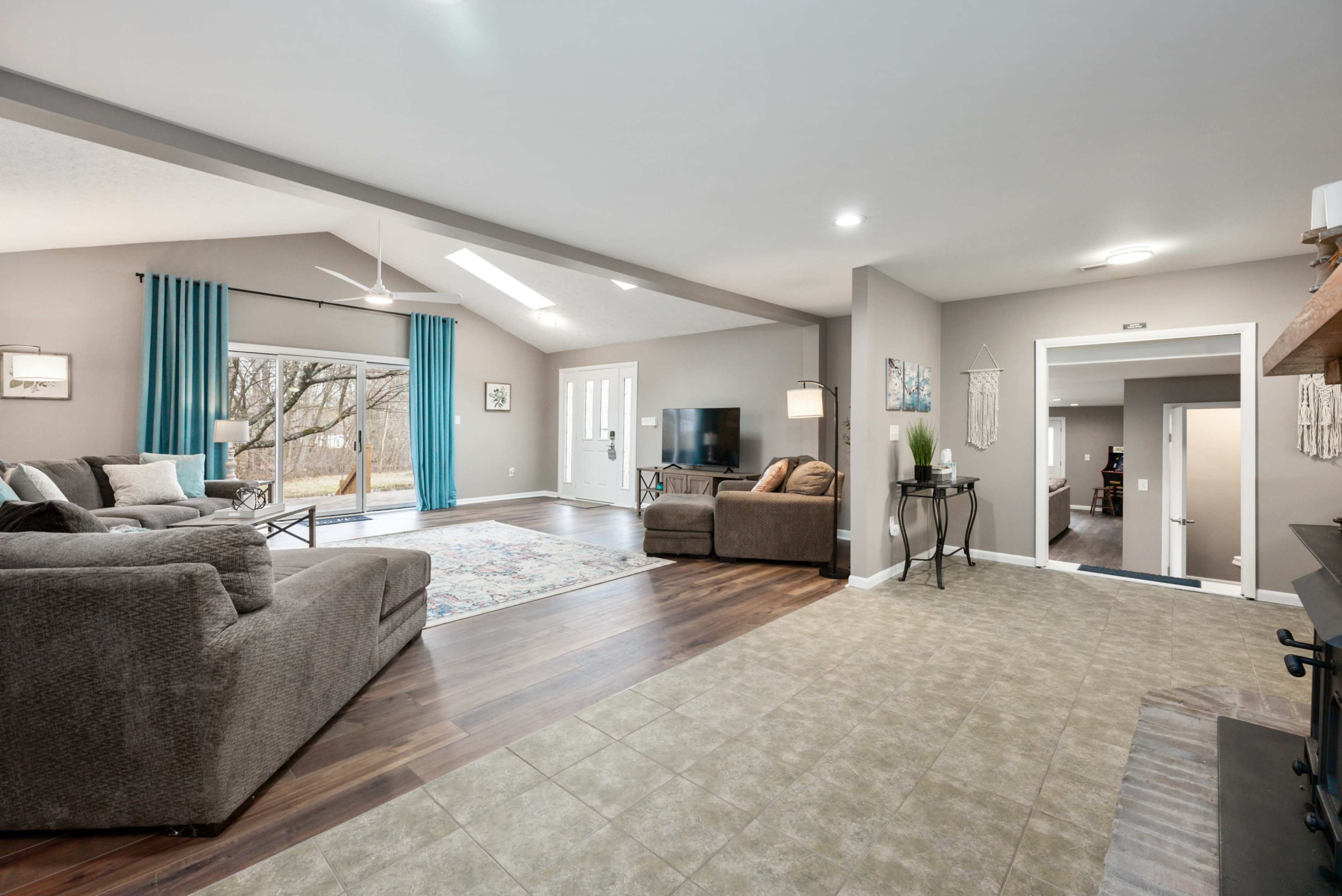 A spacious living room features two seating areas, large windows, and a view of the outdoors.