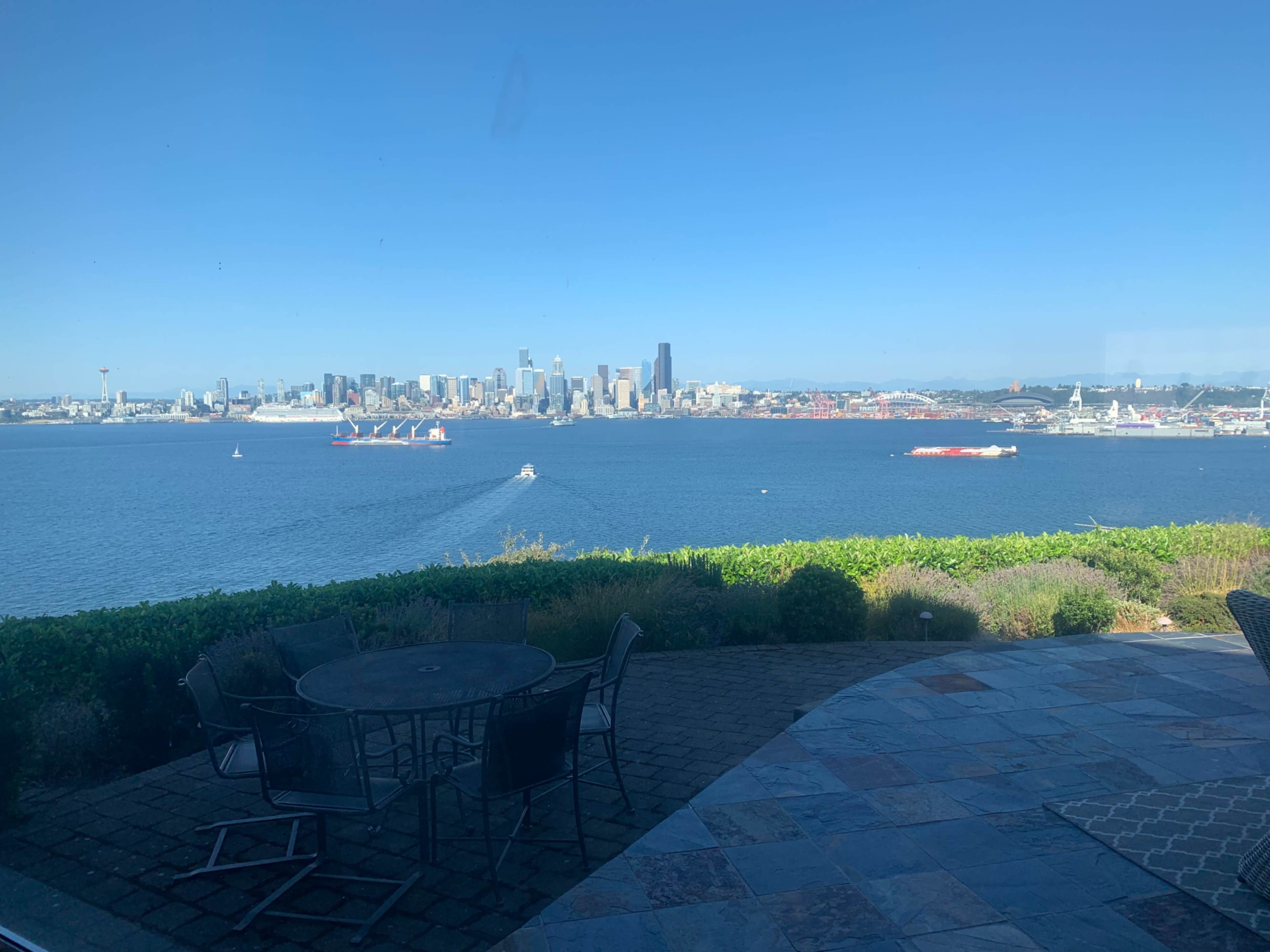 A view of a city skyline across the water with boats and a patio set in the foreground.