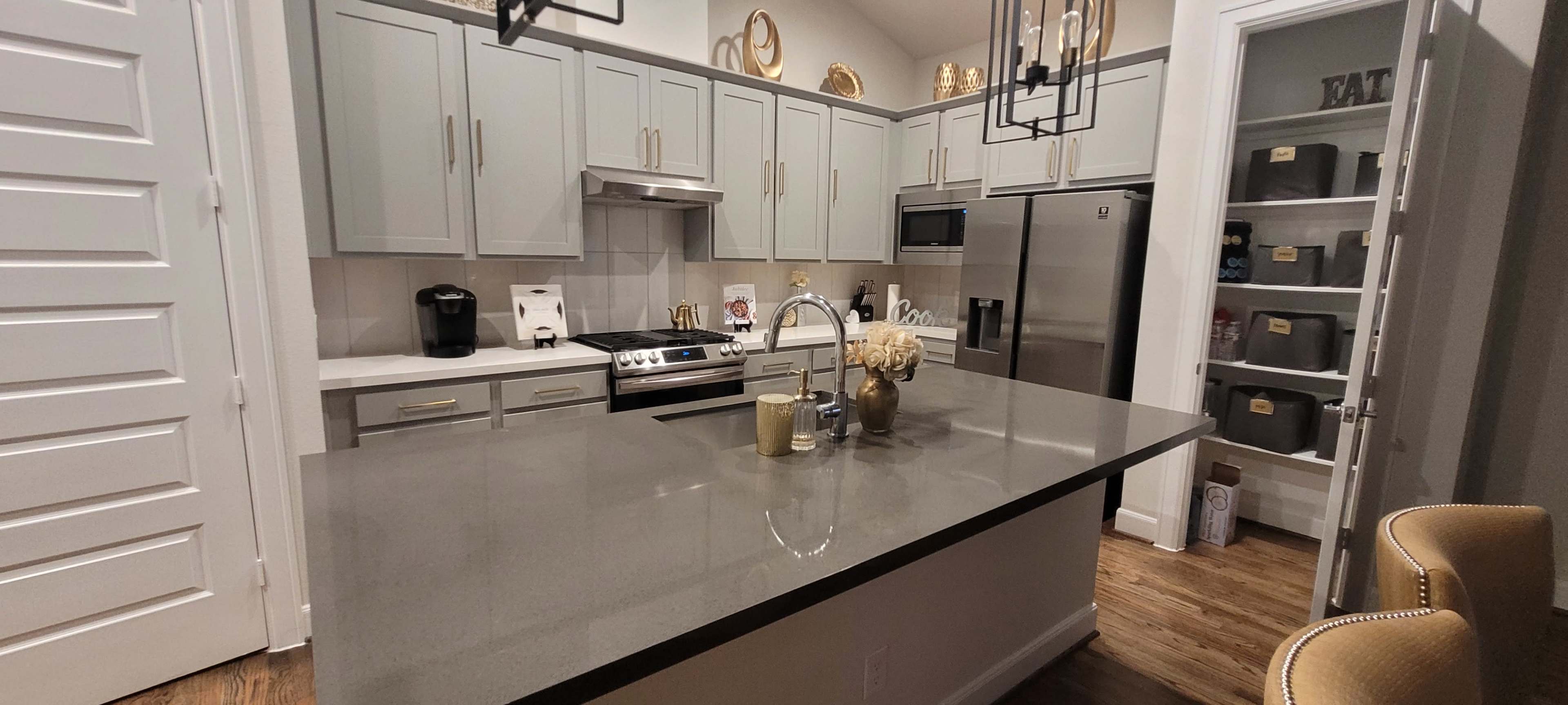 A modern kitchen features gray cabinets, stainless steel appliances, and a large island with a sink and decorative items.