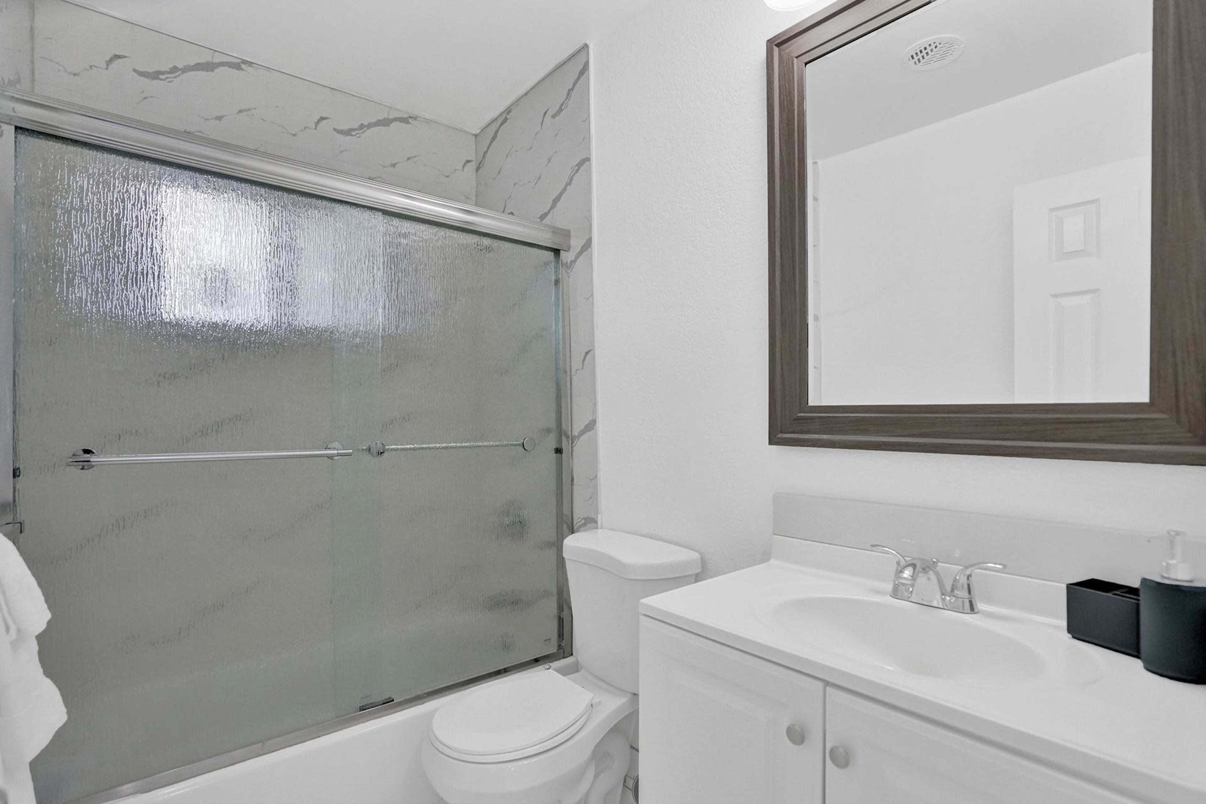 A bathroom featuring a glass shower door, a white vanity with a sink, and a mirror above it.