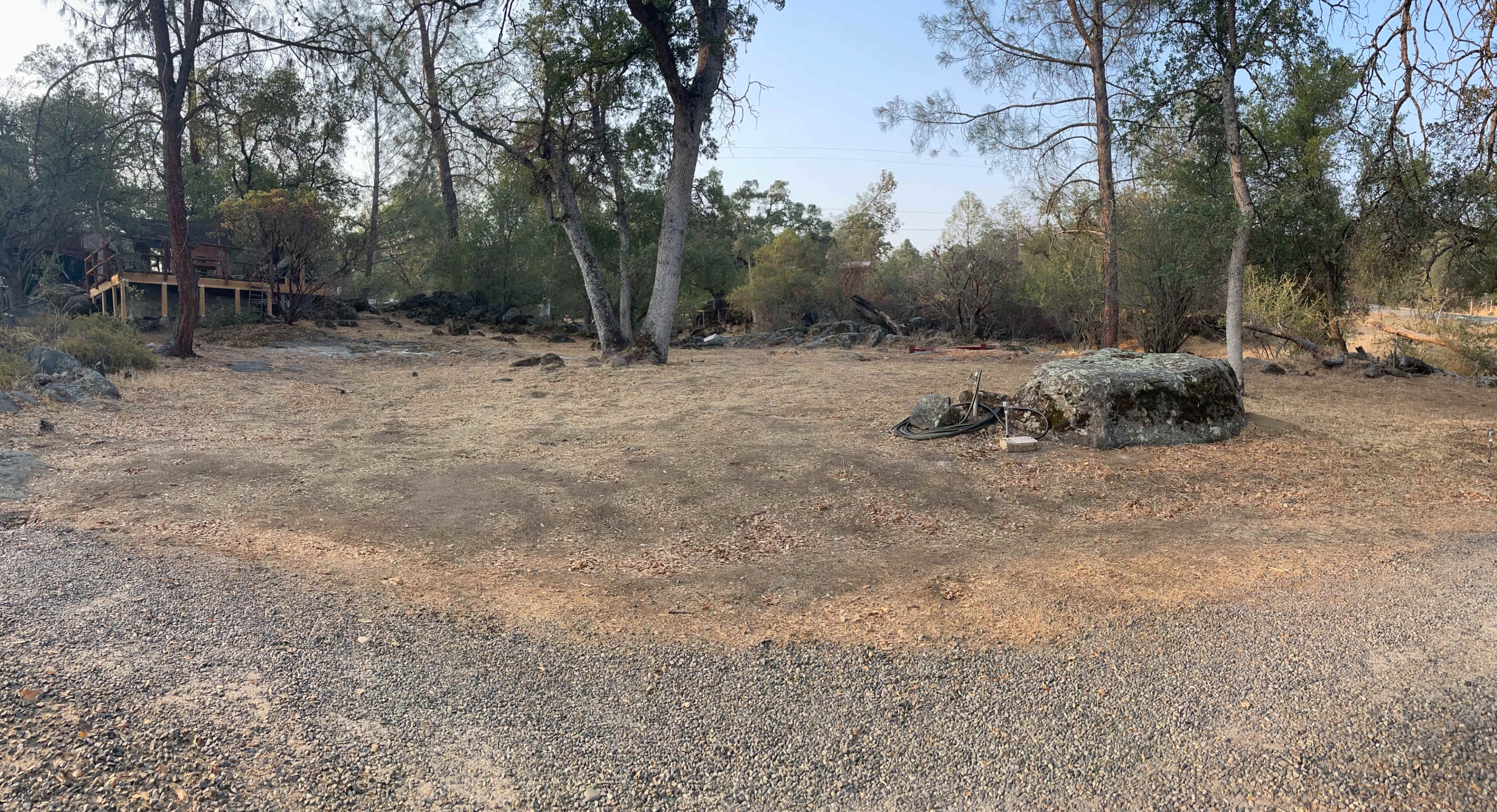A cleared, rocky area surrounded by trees and sparse vegetation.