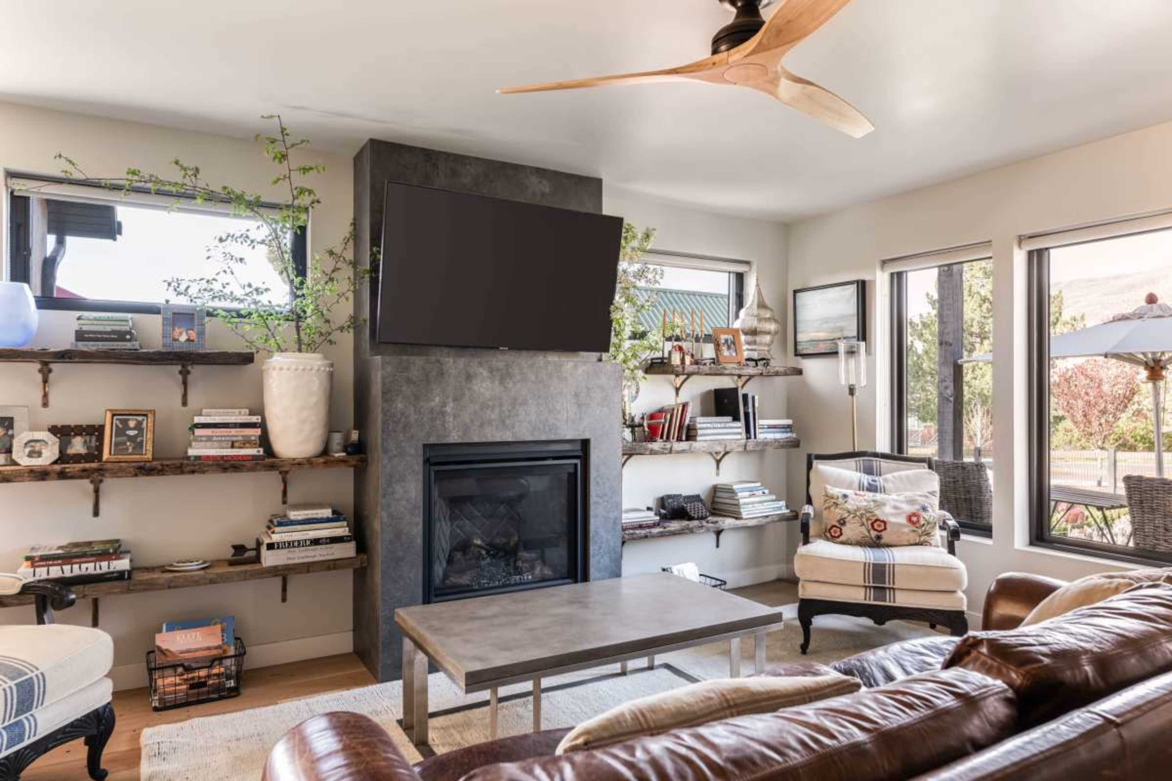 The living room features a modern fireplace with a television mounted above it, surrounded by built-in shelves filled with books and decorative items.