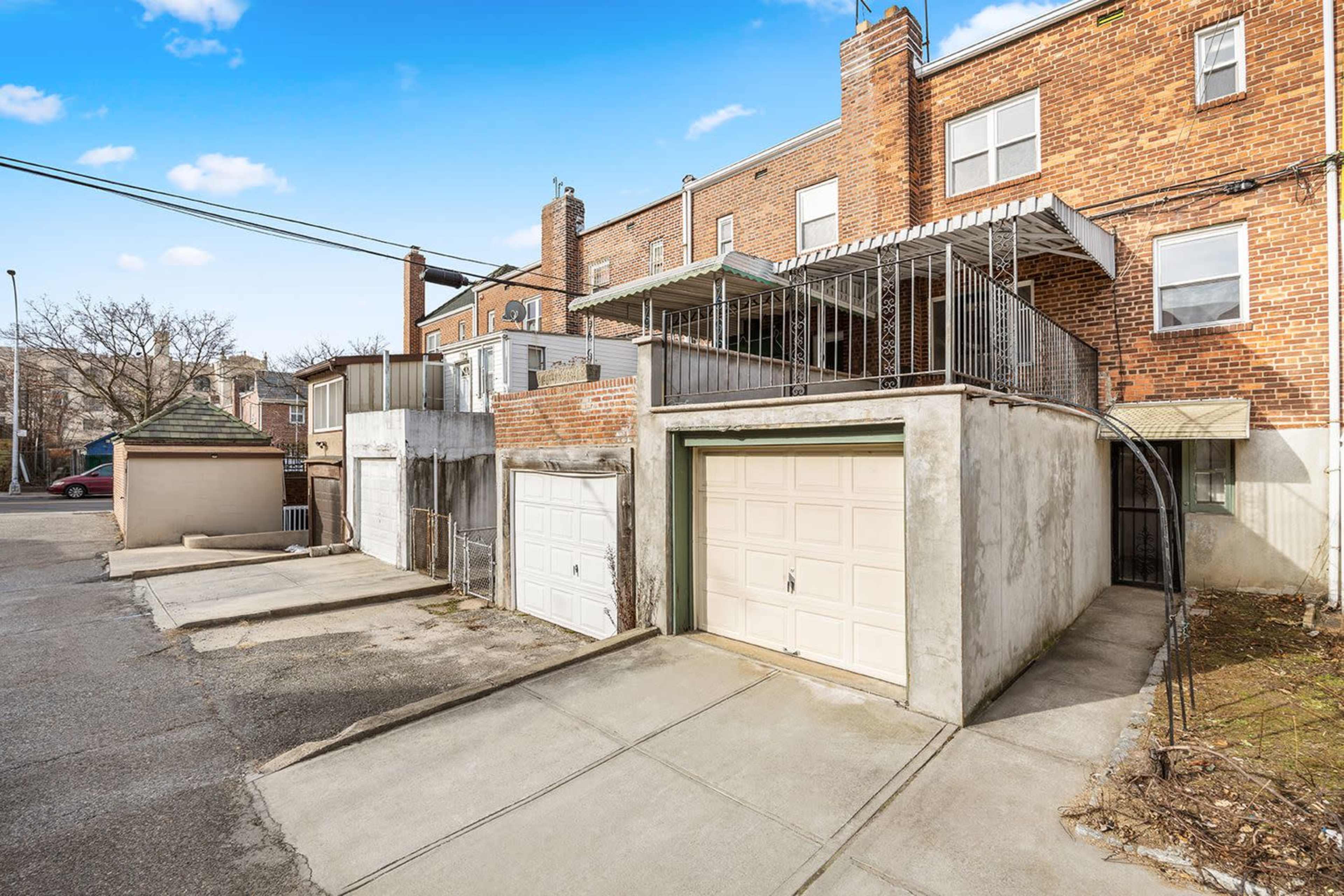 The image shows a two-story brick building with a garage on the left and a small patio area above the garage.