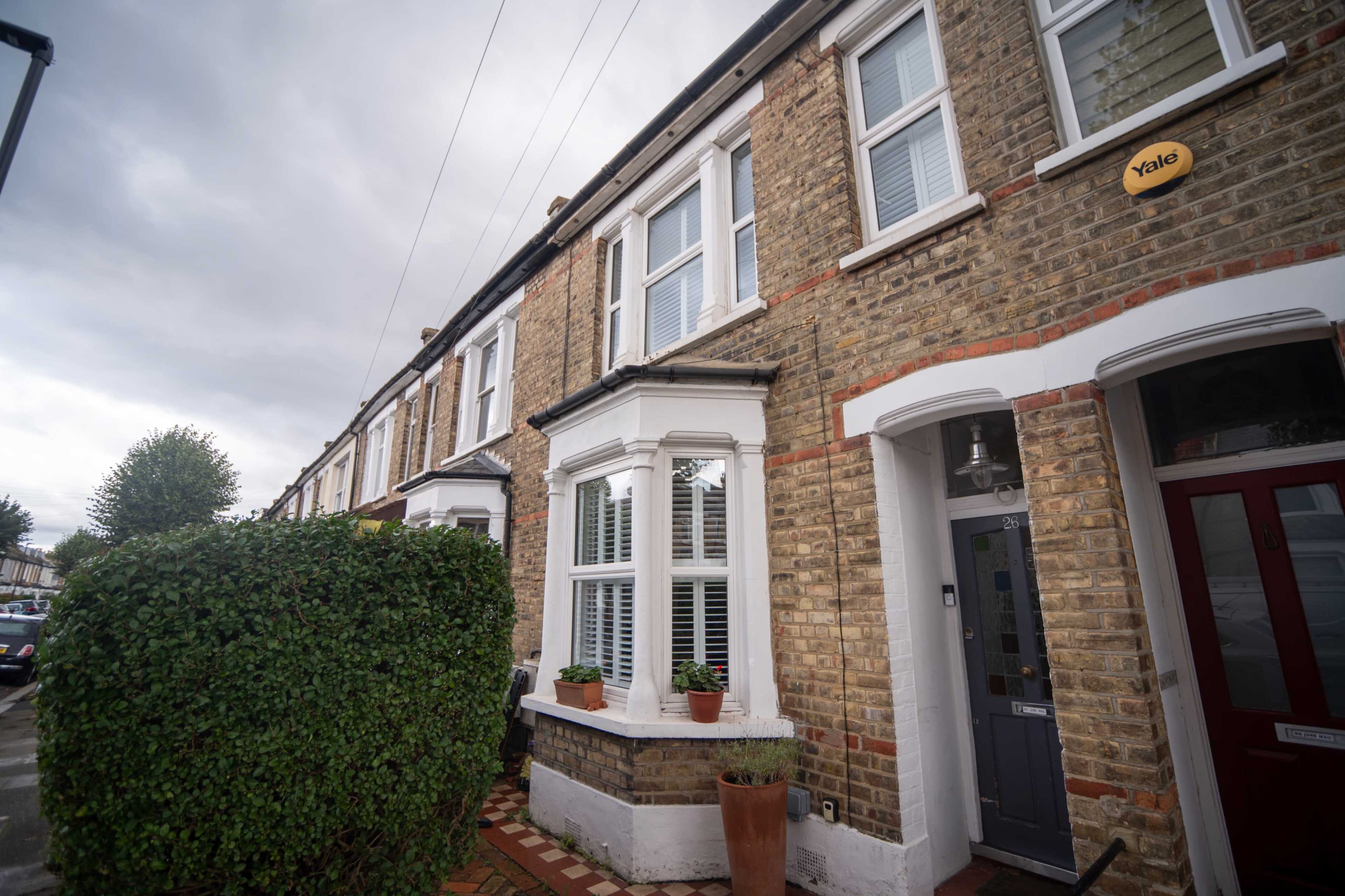 A row of brick houses features white window frames and potted plants at the entrance, with a sign labeled "Yale" on one of the doors.