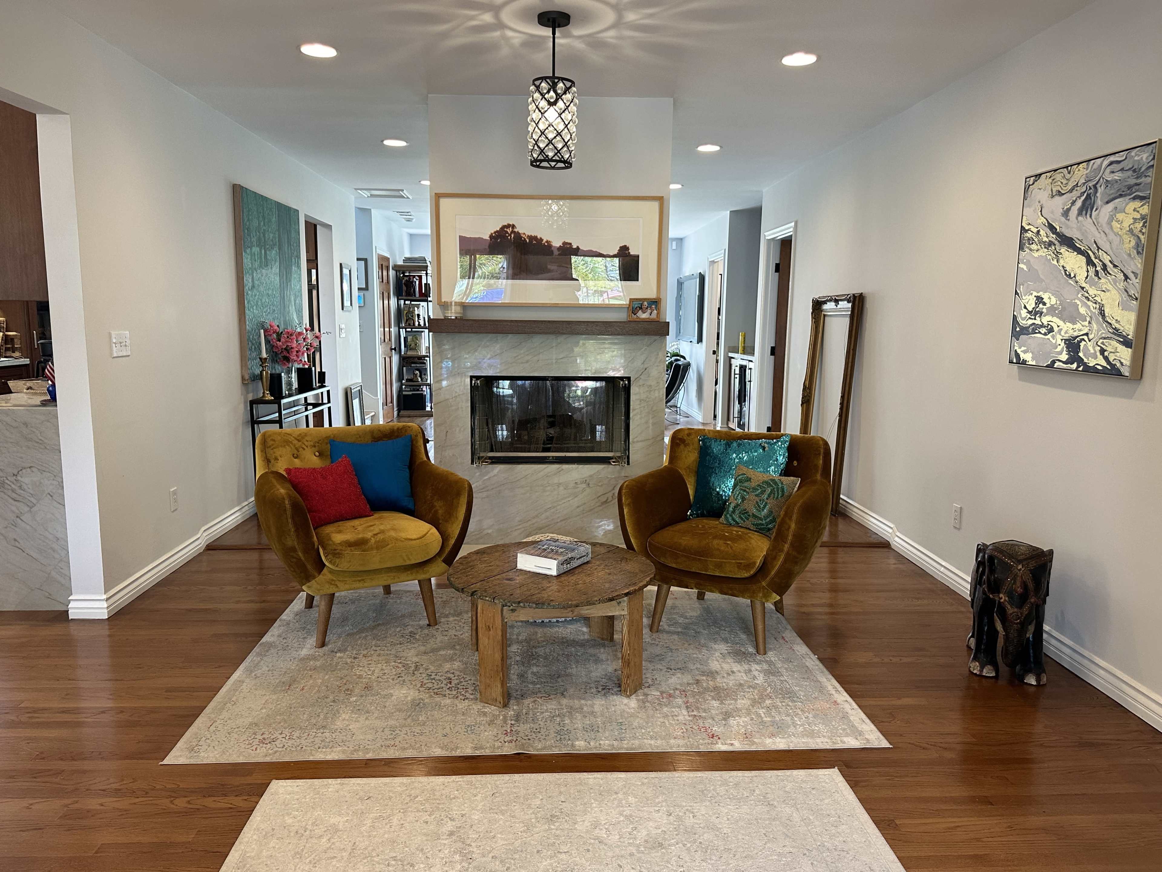 A living room with two upholstered chairs, a round wooden coffee table, and a cozy fireplace, all set on a large area rug.
