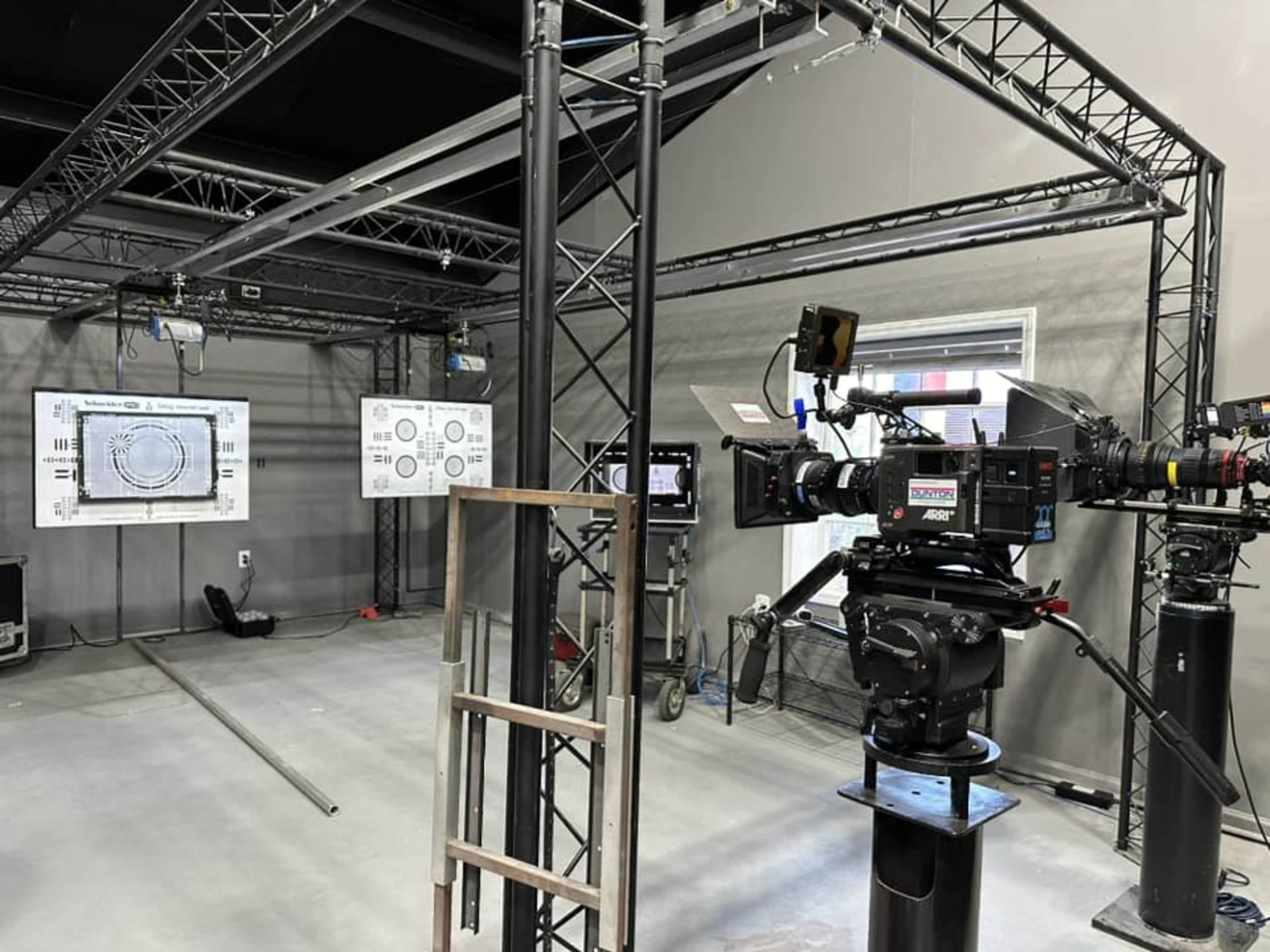 A film production studio featuring multiple cameras, monitors, and a steel framework set up for shooting.