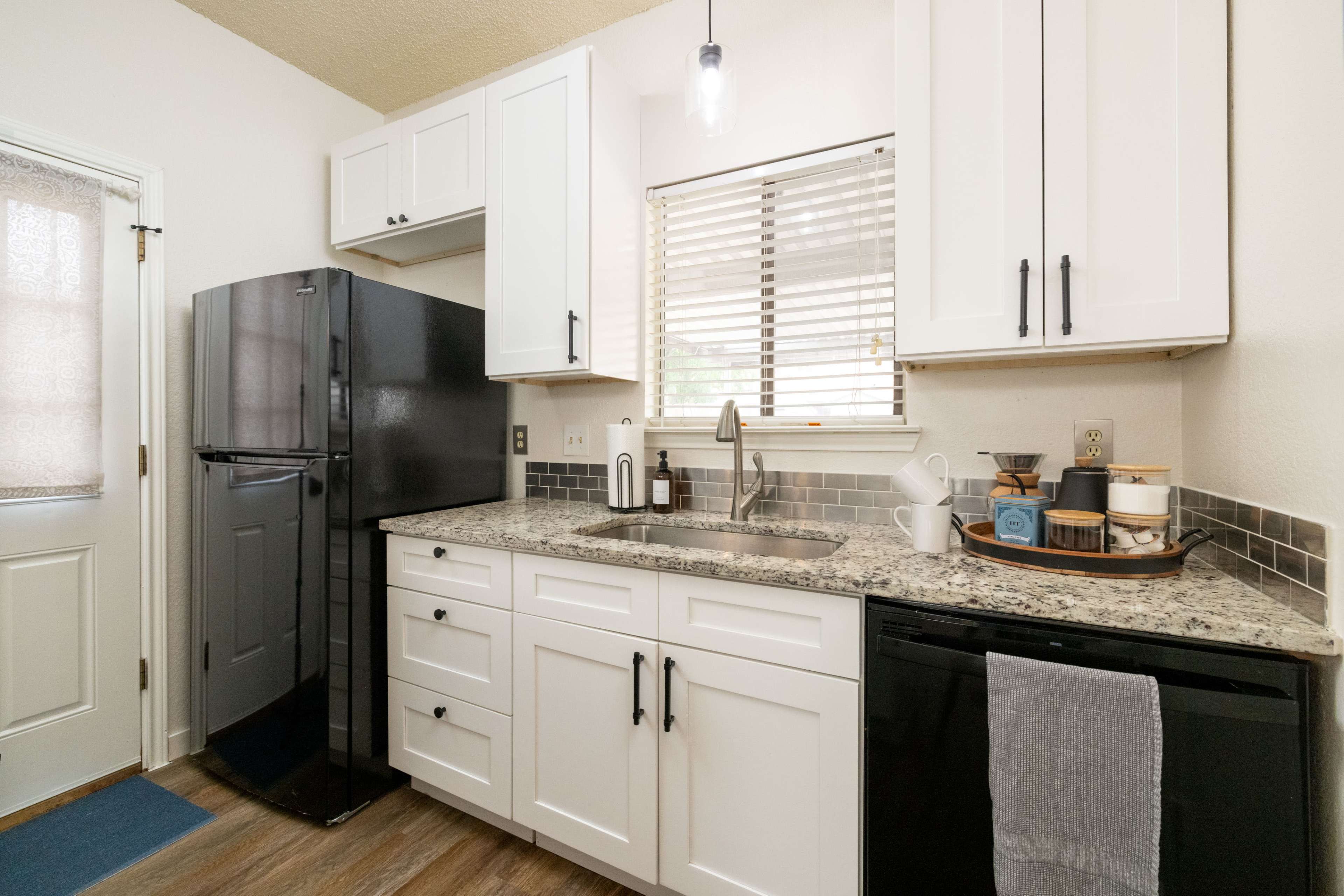 The image shows a compact kitchen with black appliances, white cabinets, and a granite countertop.