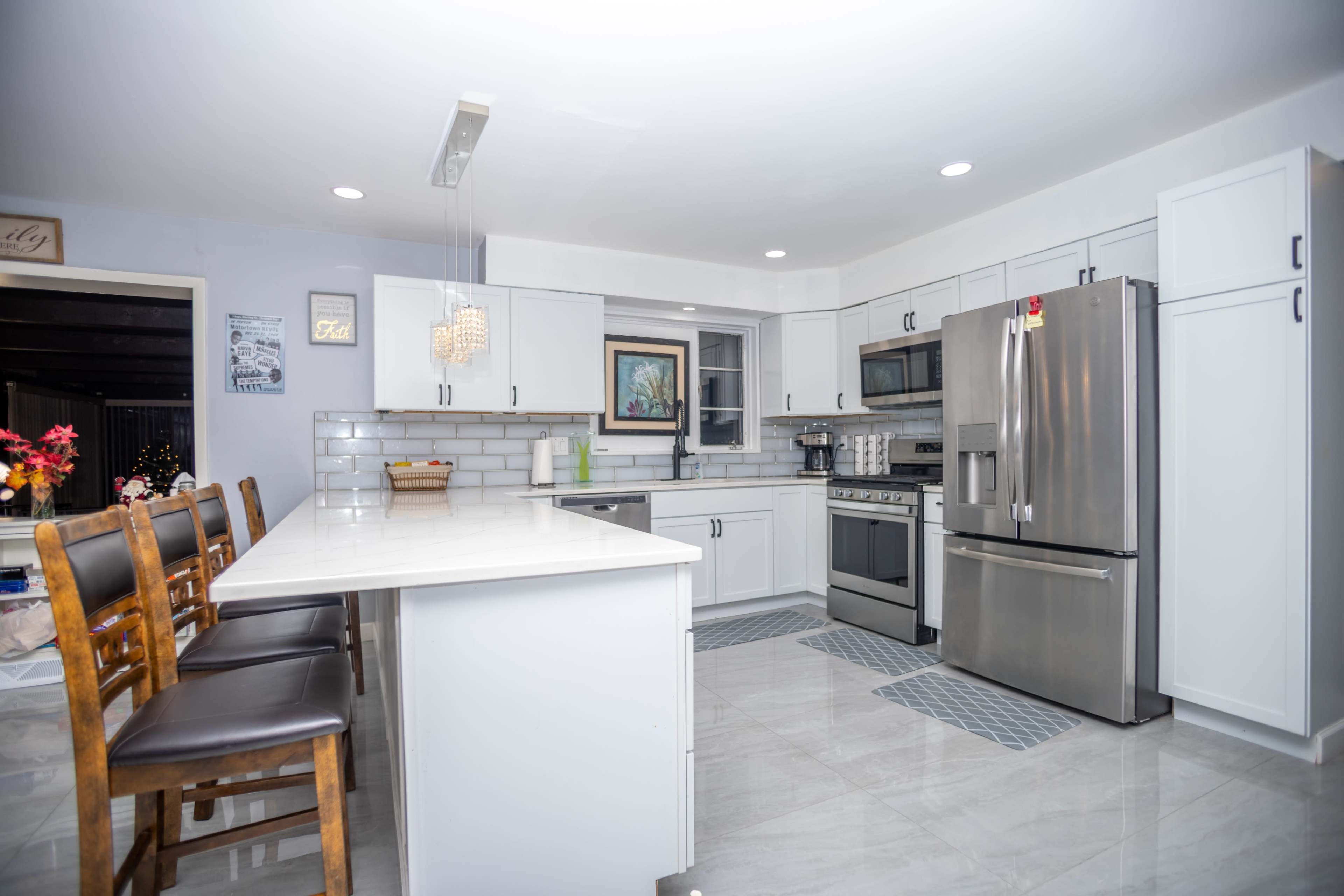 The kitchen features modern appliances, a long island with bar seating, and white cabinetry with gray countertops.