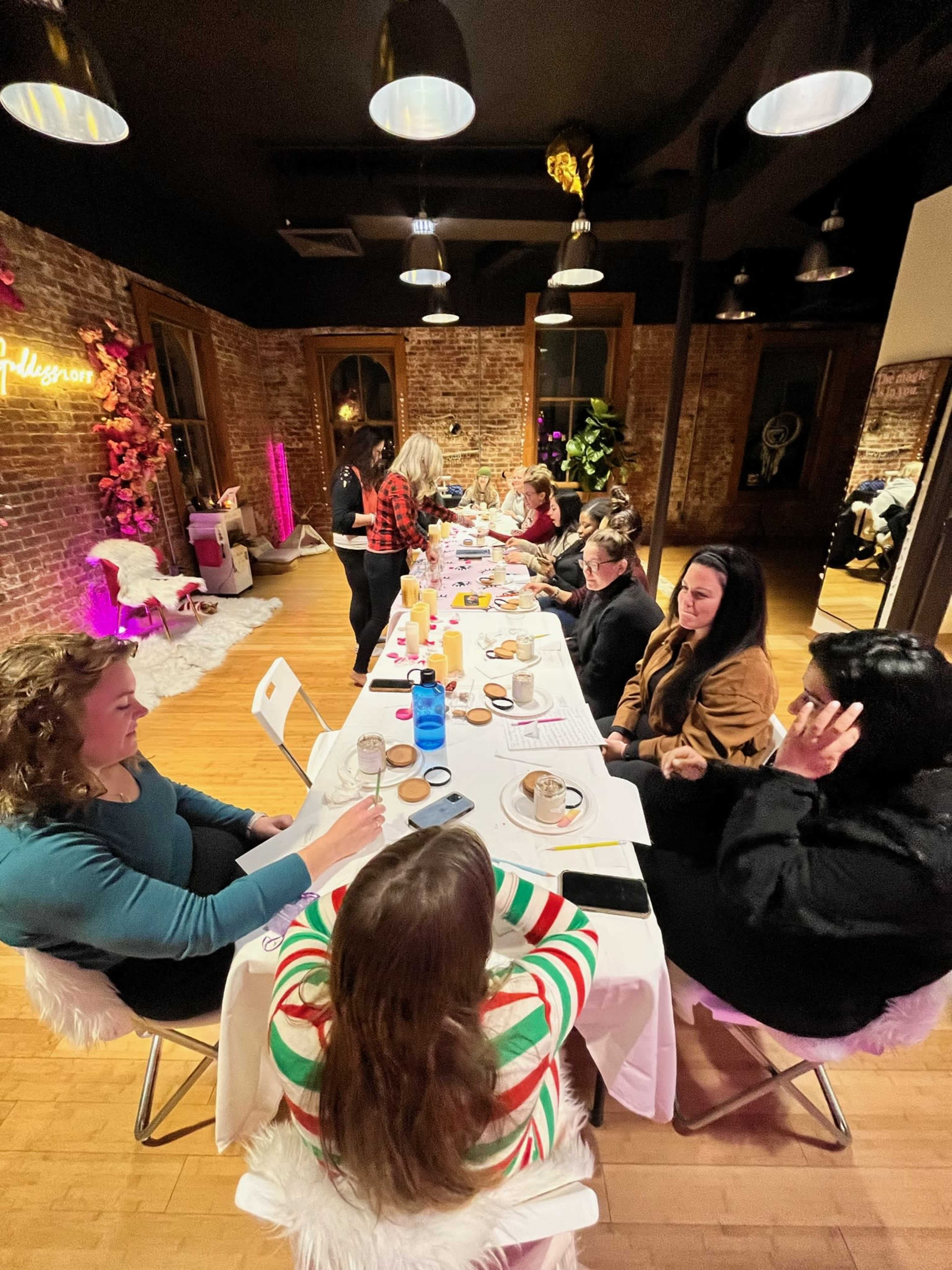 A long table filled with various drinks and desserts is set in a well-decorated room where a group of people are engaged in conversation.