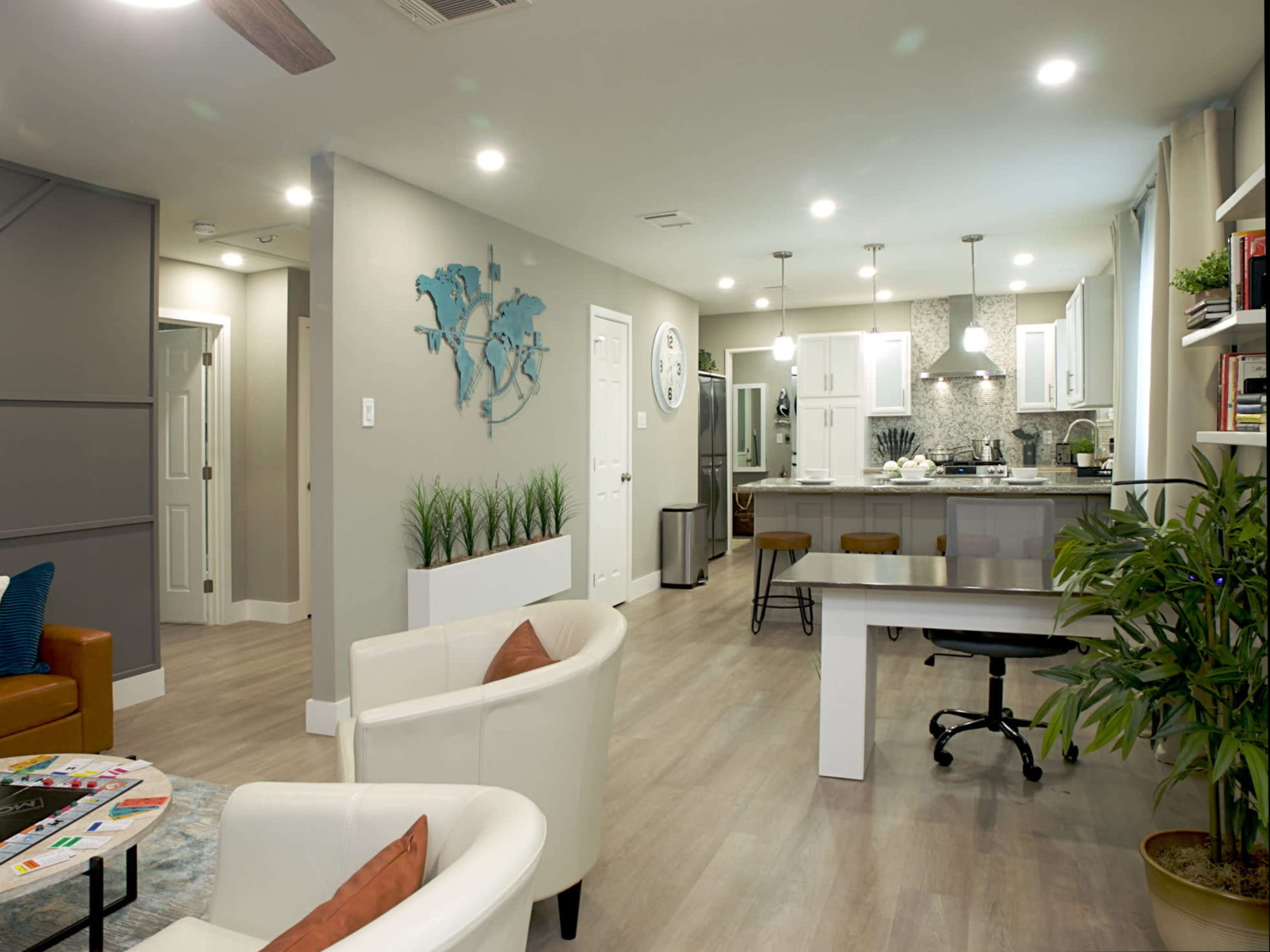 A modern open-concept living space featuring a kitchen, dining area, and seating area with minimalist decor.