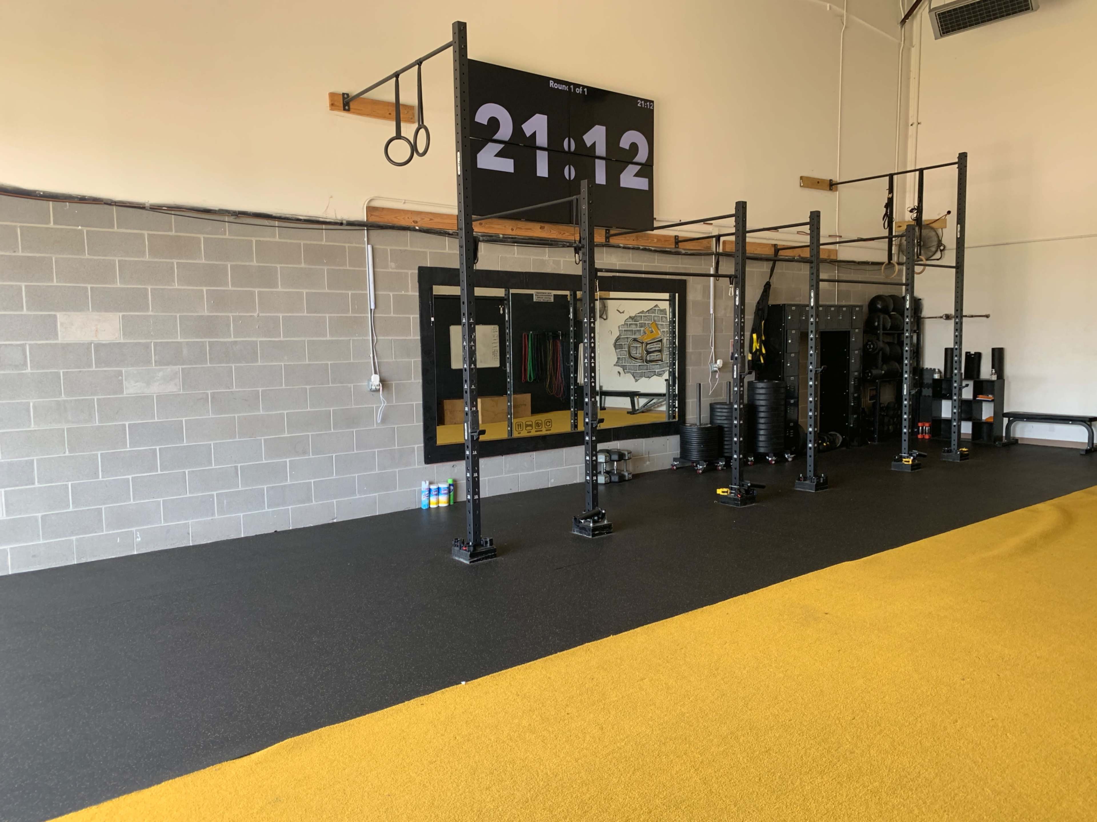 A workout space equipped with fitness apparatus, a digital timer display, and a large mirror on the wall.