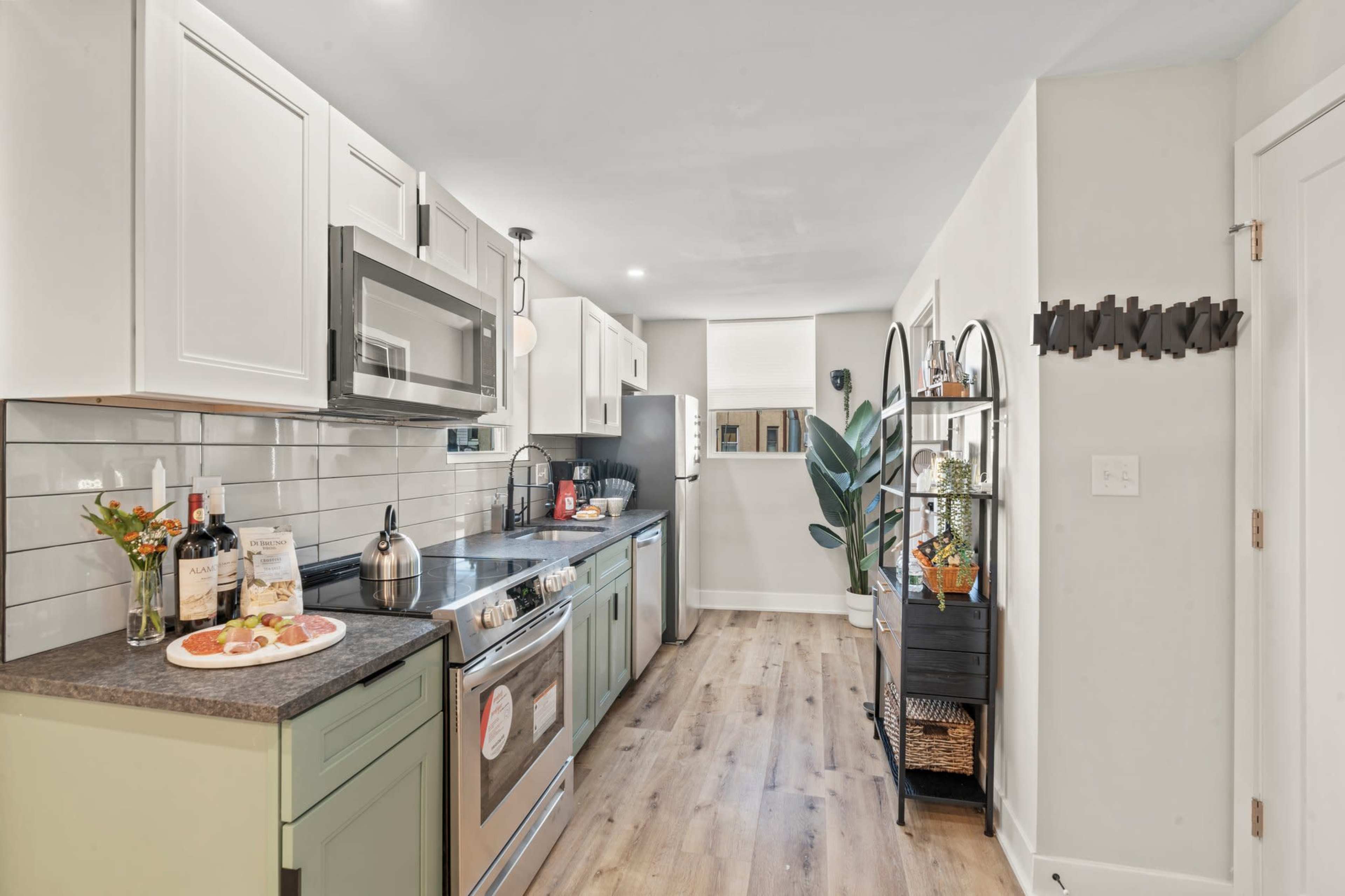 The kitchen features light-colored cabinetry, stainless steel appliances, a stone countertop, and a small dining area with a platter of snacks.