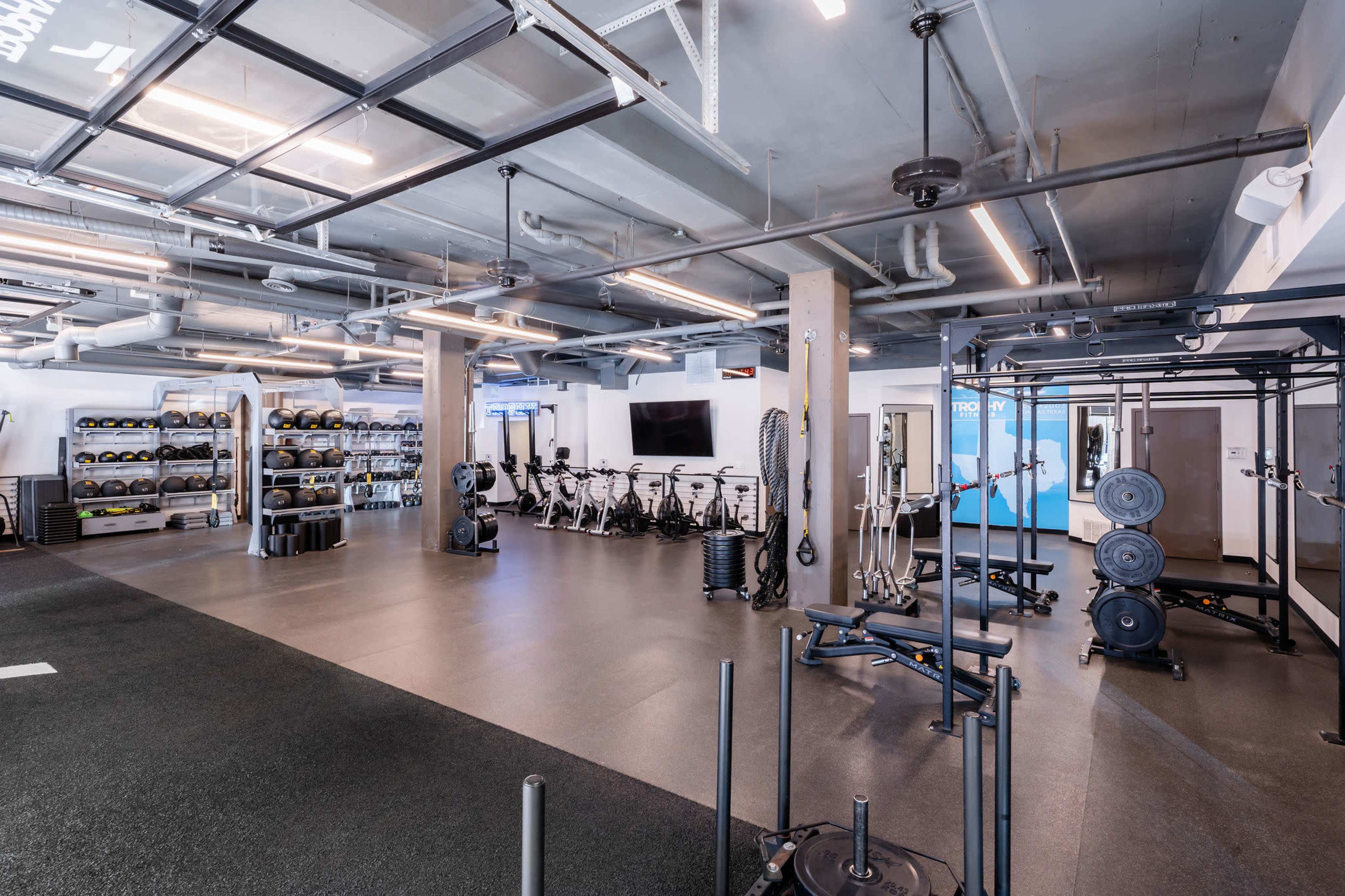 A spacious gym with exercise equipment, including weights and stationary bikes, organized neatly within a well-lit environment.