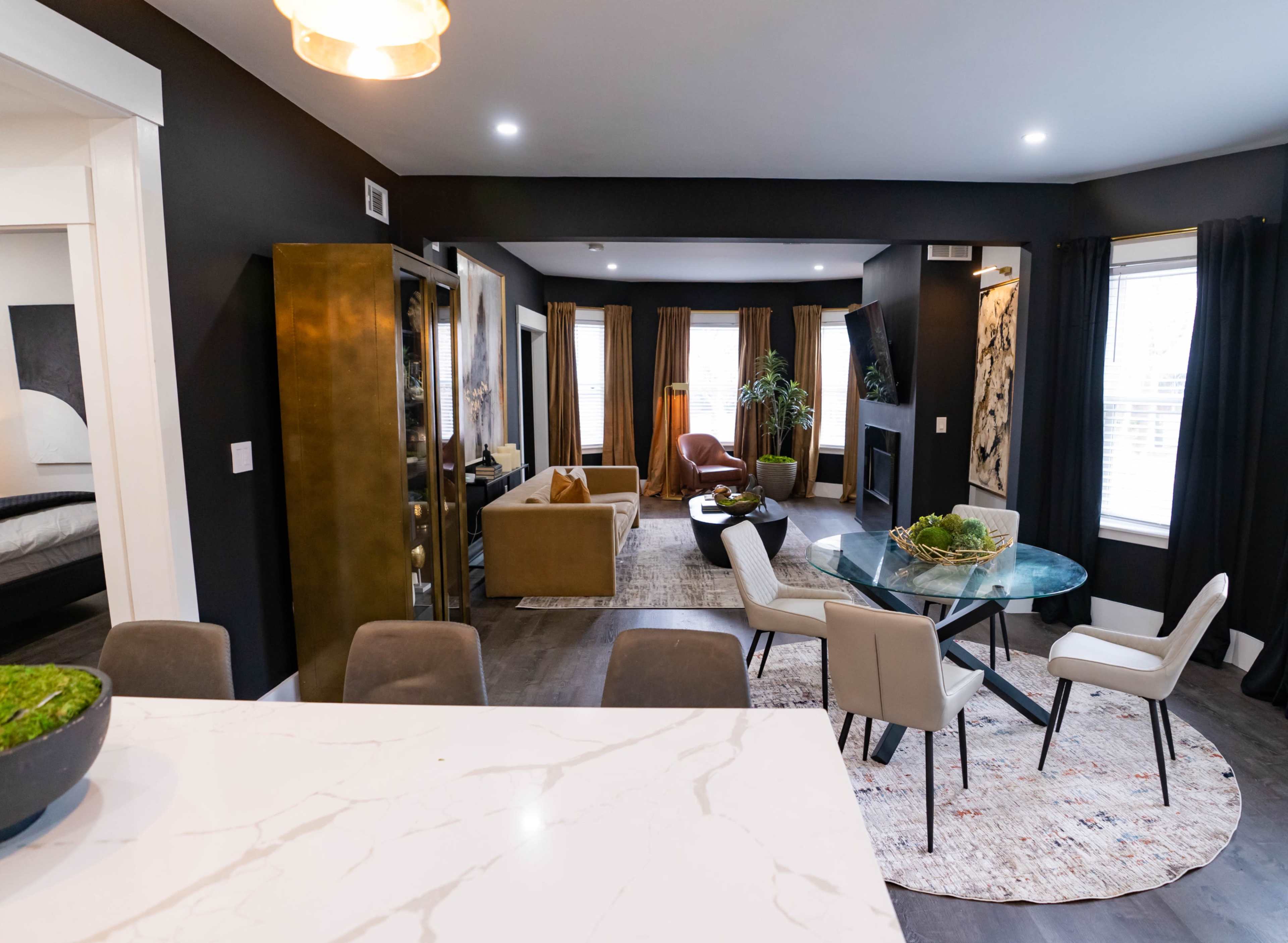 A modern open-concept living area with a dining table, seating areas, and large windows providing natural light.