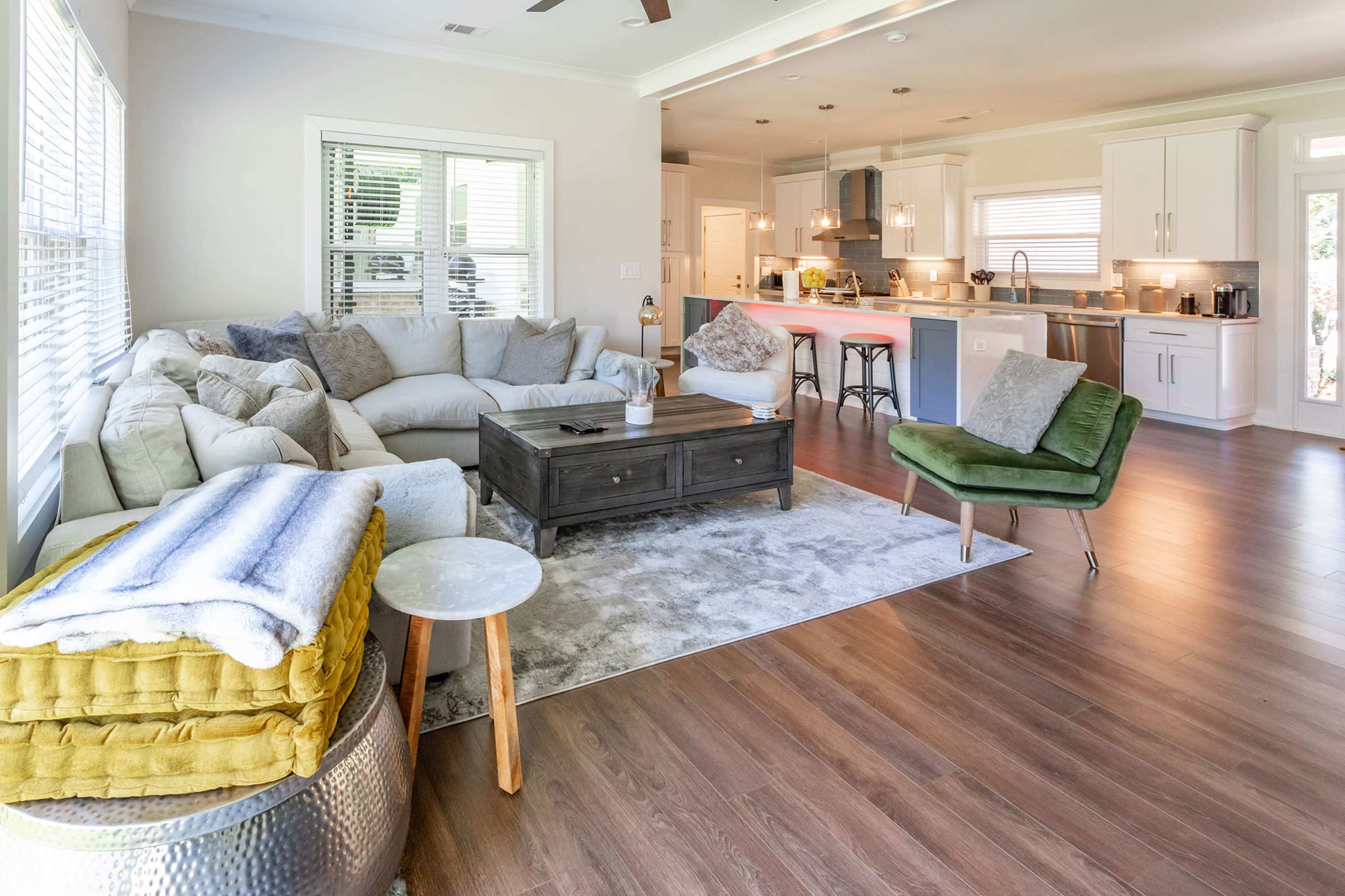 A spacious living room with a large sectional sofa, a coffee table, and a view of a modern kitchen in the background.