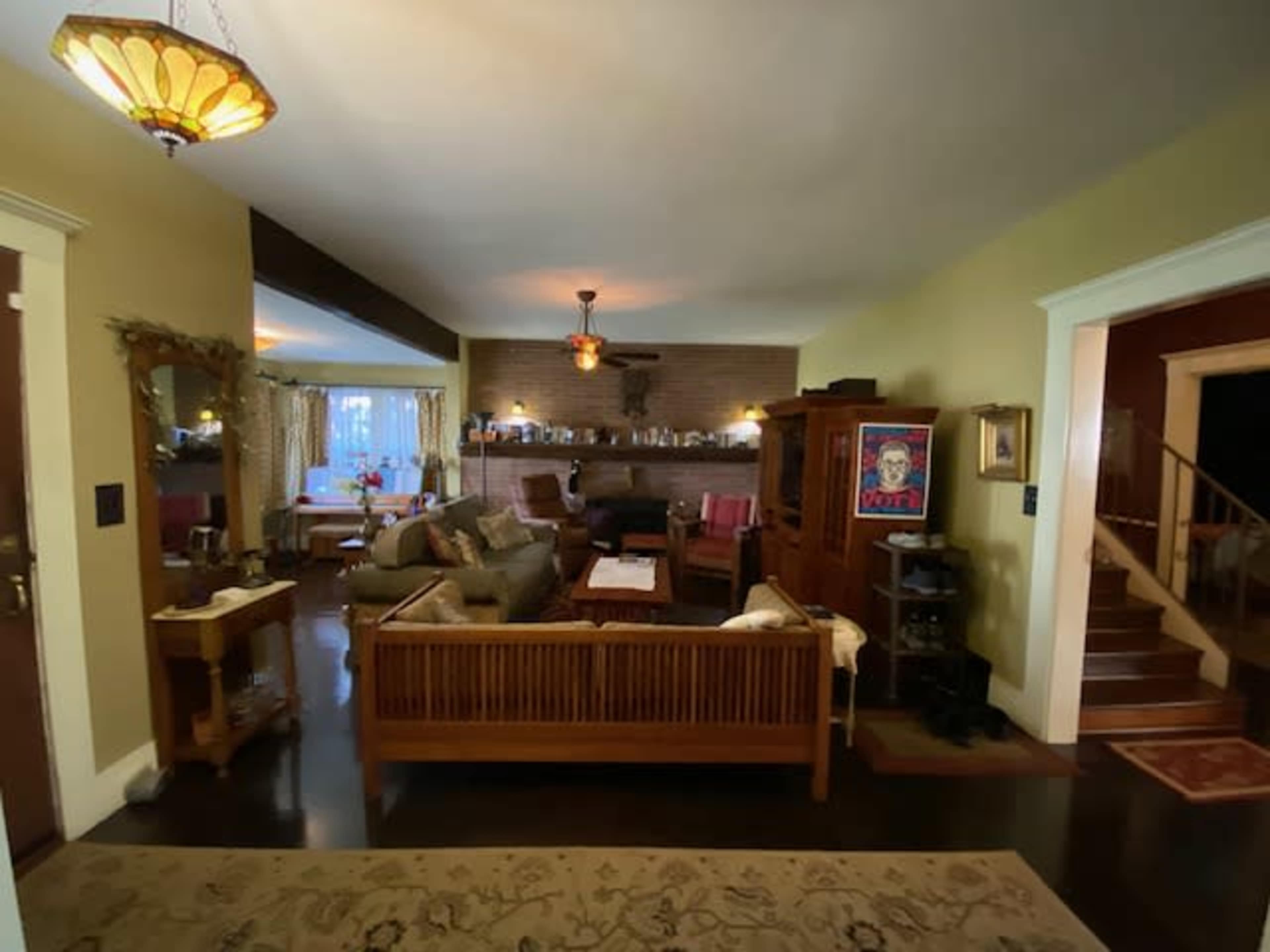 A cozy living room with a seating area, a fireplace, and warm lighting, featuring wooden furniture and decorative accents.