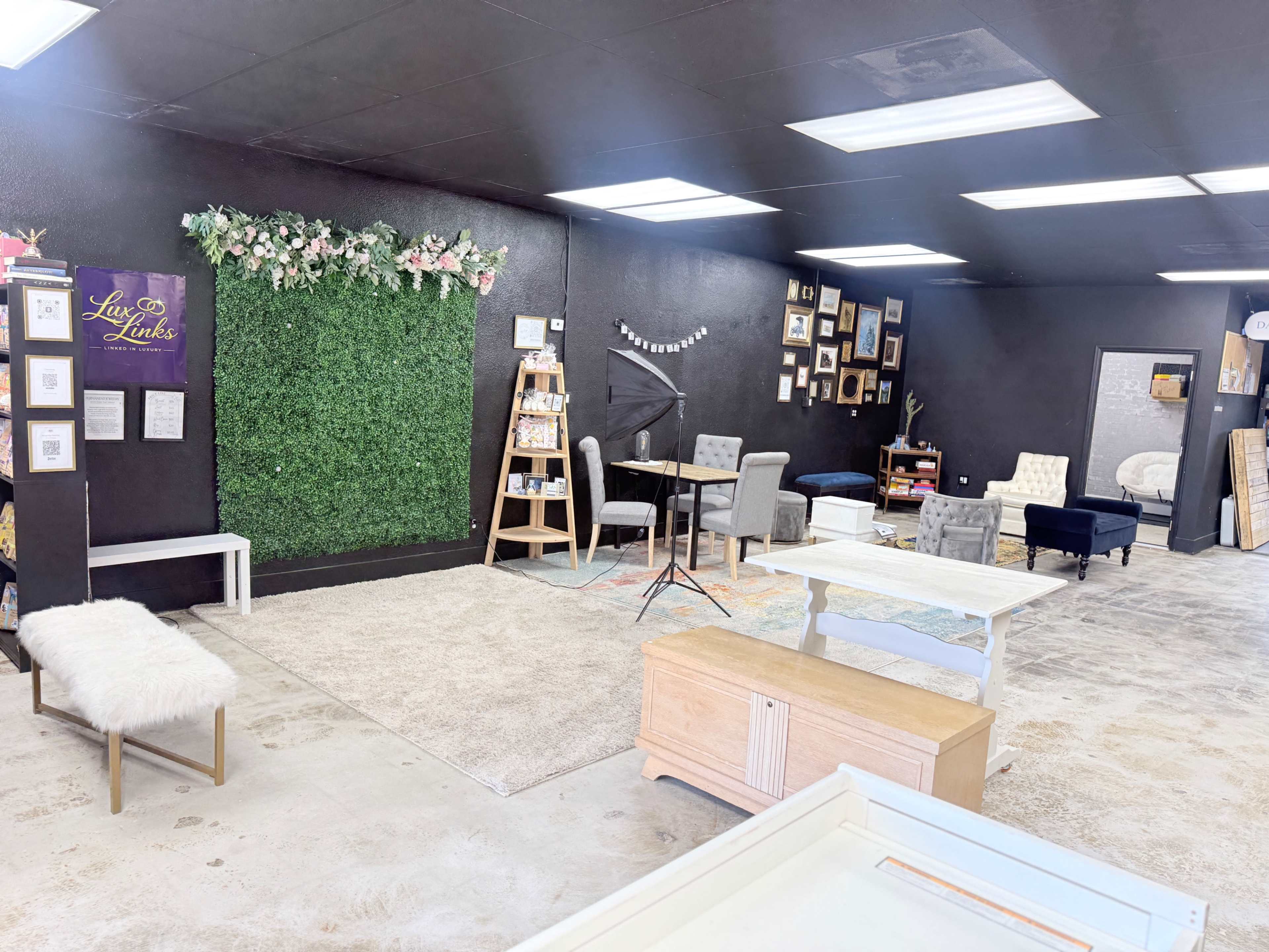 The image shows an interior space with black walls, a green wall decorations, several seating areas, and various framed pictures displayed on the walls.