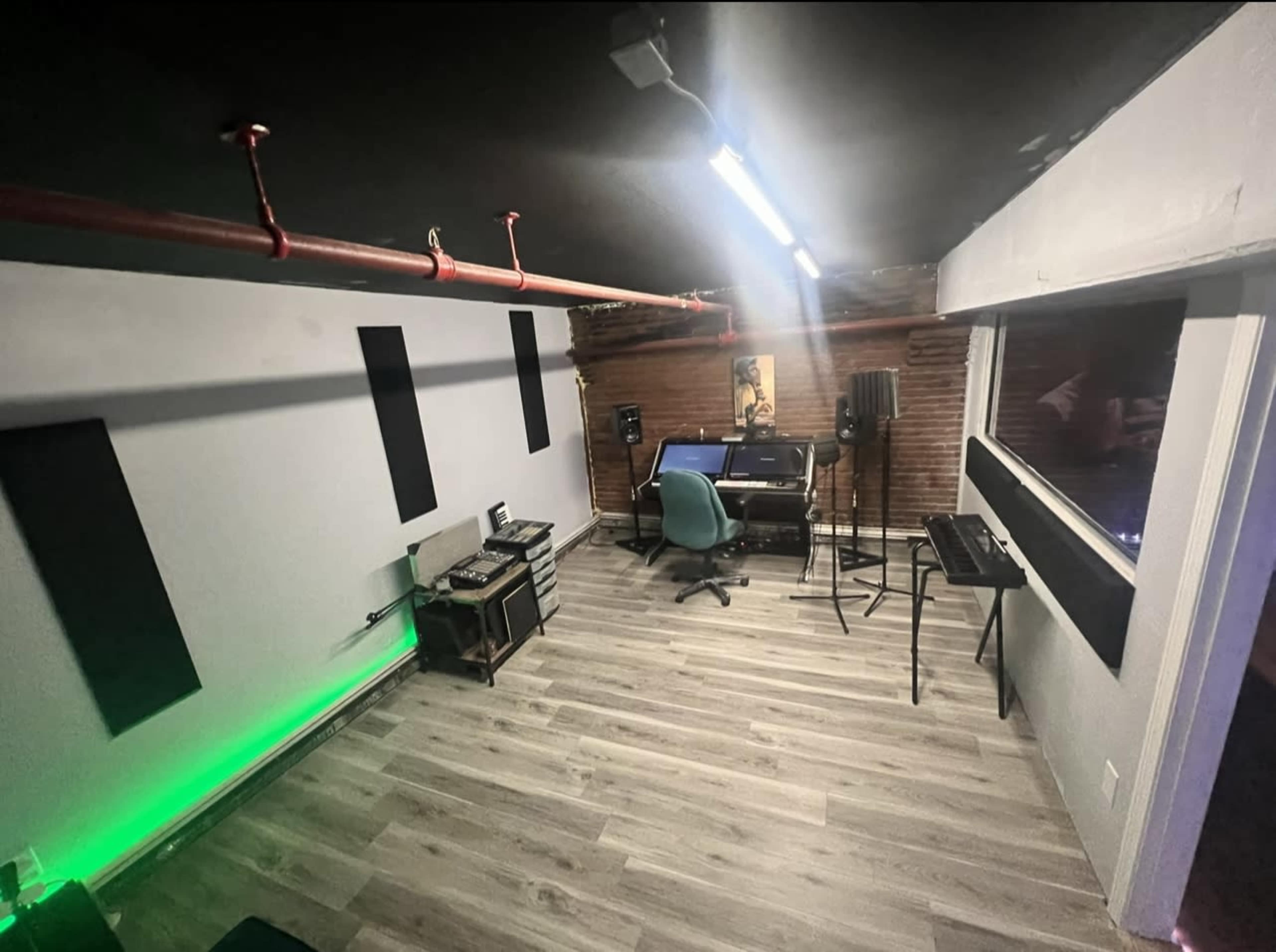 A home recording studio features a computer desk with musical equipment, acoustic panels, and ambient lighting on the walls.