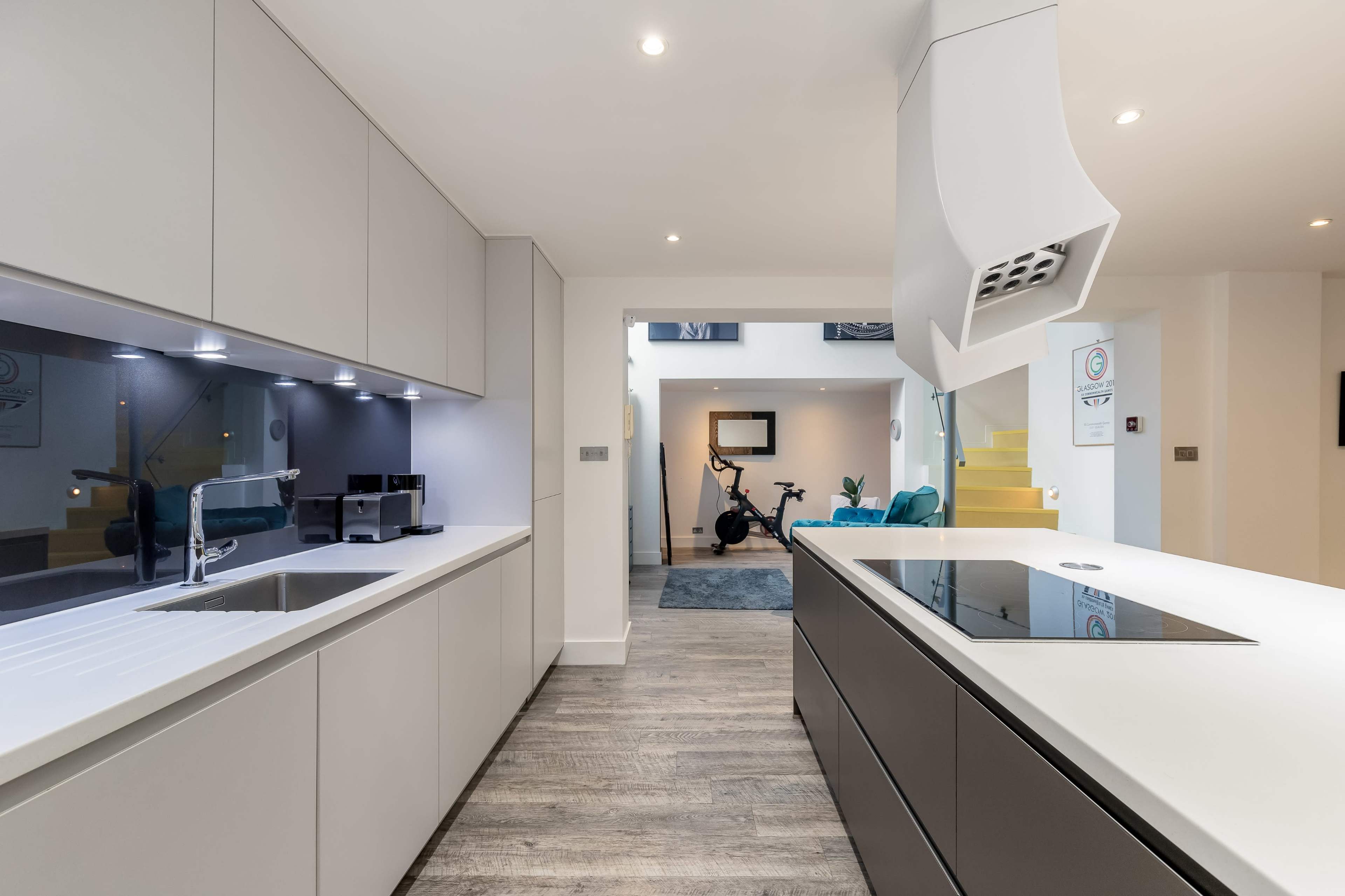 A modern kitchen with sleek cabinetry, a central island featuring a cooktop, and recessed lighting illuminating the space.