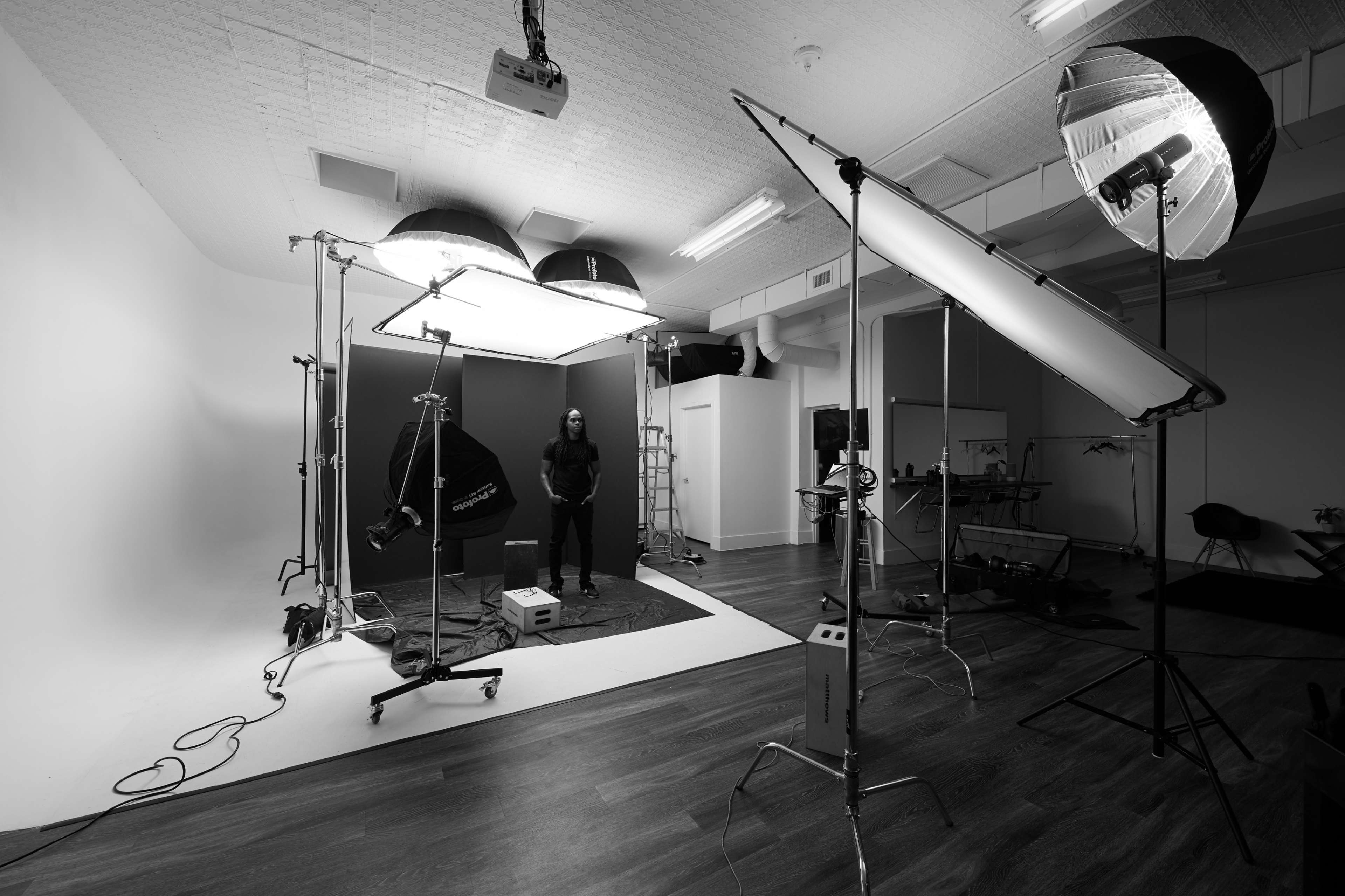 A photography studio is set up with various lighting equipment and a model positioned in the center.
