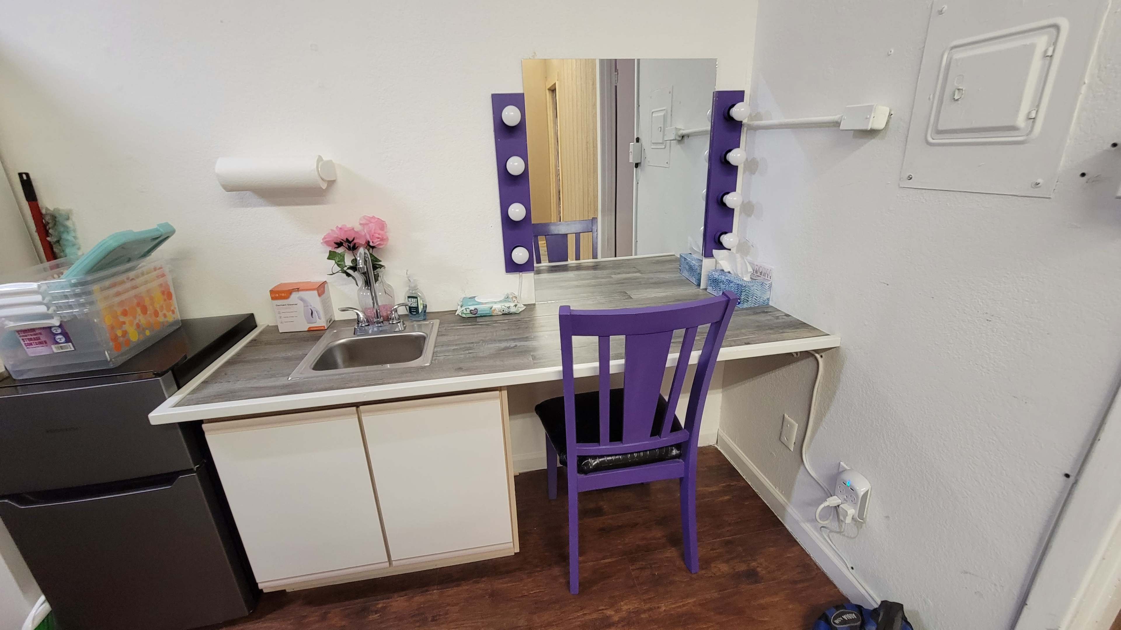 A small vanity area with a mirror, a sink, a chair, and various beauty products neatly arranged on the counter.