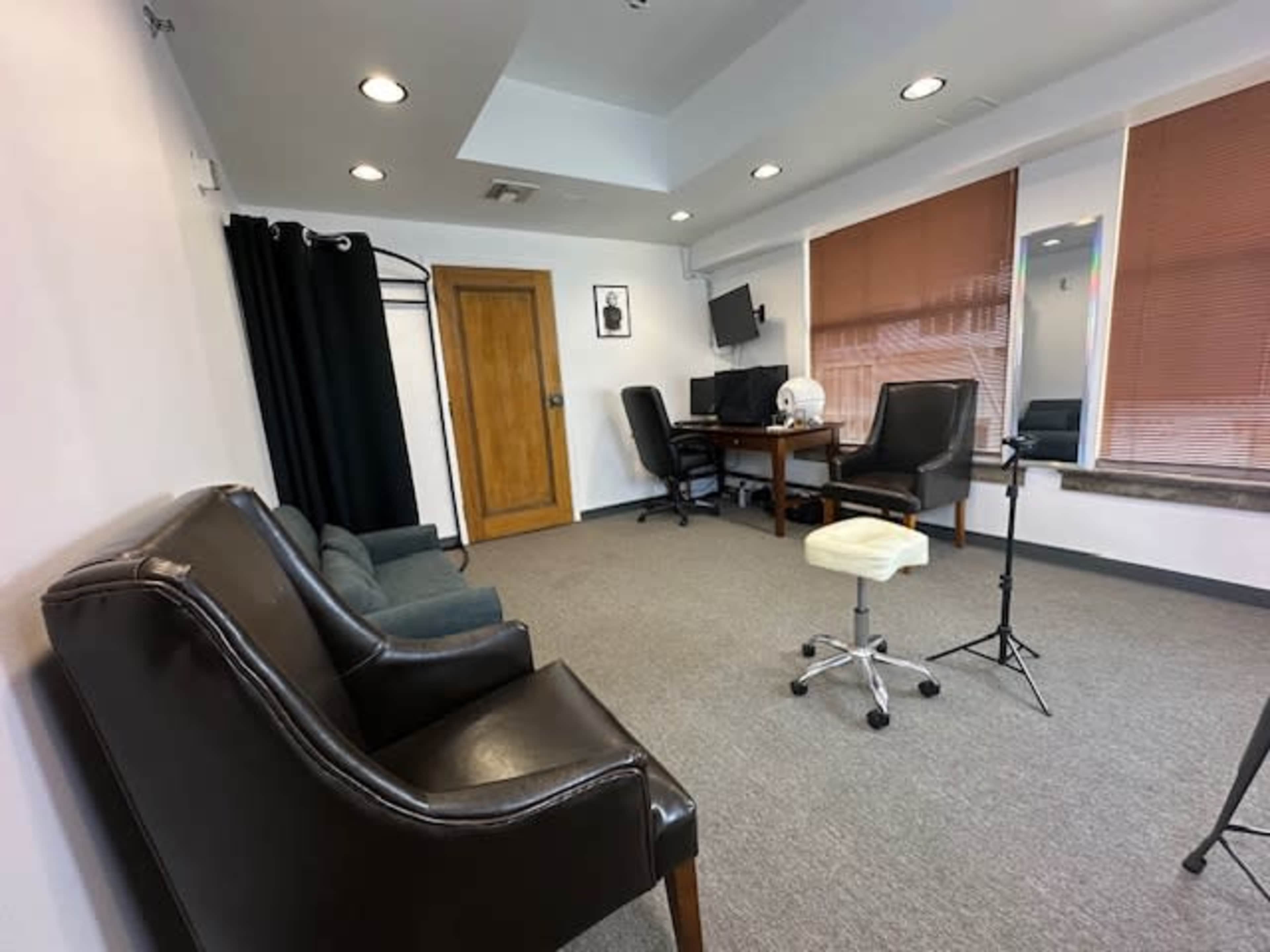 The image shows a sparsely furnished office space featuring two chairs, a desk with a computer, and a closet.