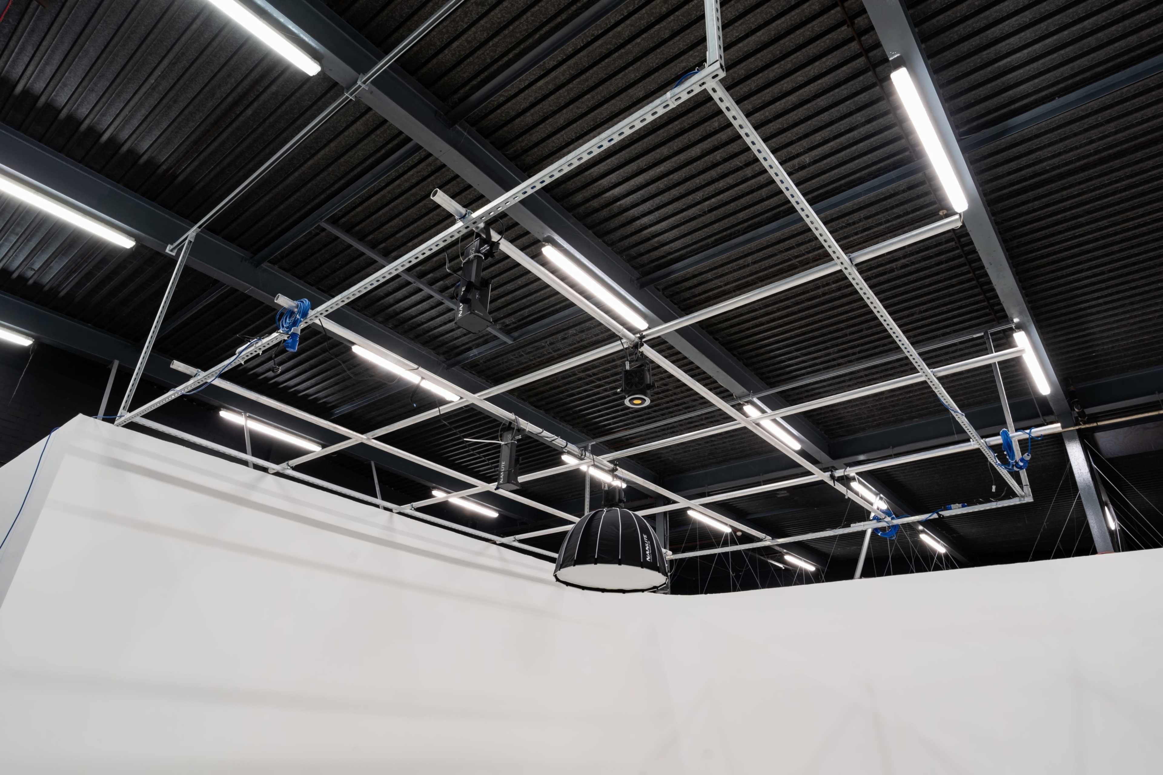 An industrial ceiling with suspended lighting fixtures and overhead tracks.