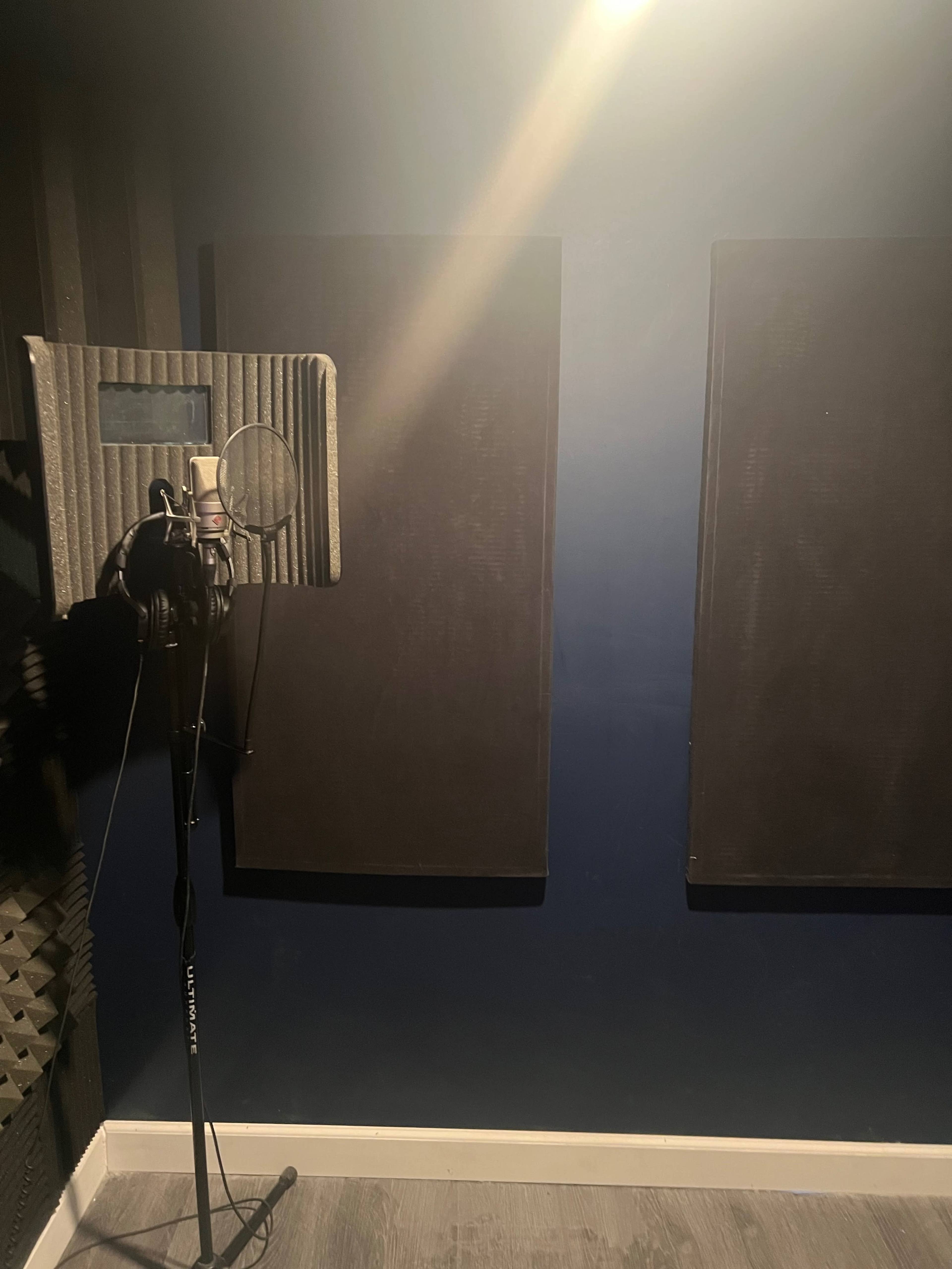 A soundproof recording studio with a microphone setup and acoustic panels on the walls.